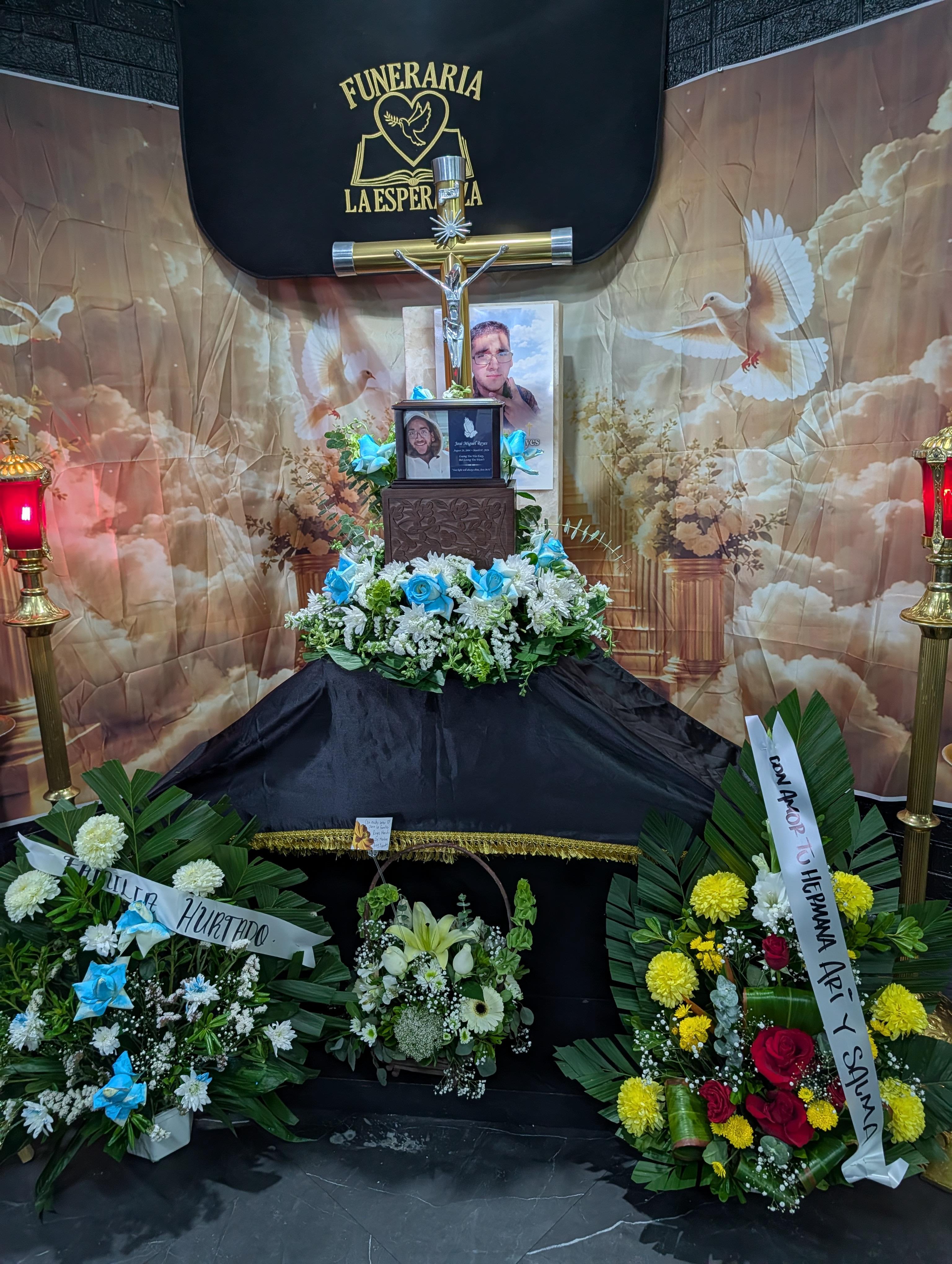 A funeral casket with flowers and a cross