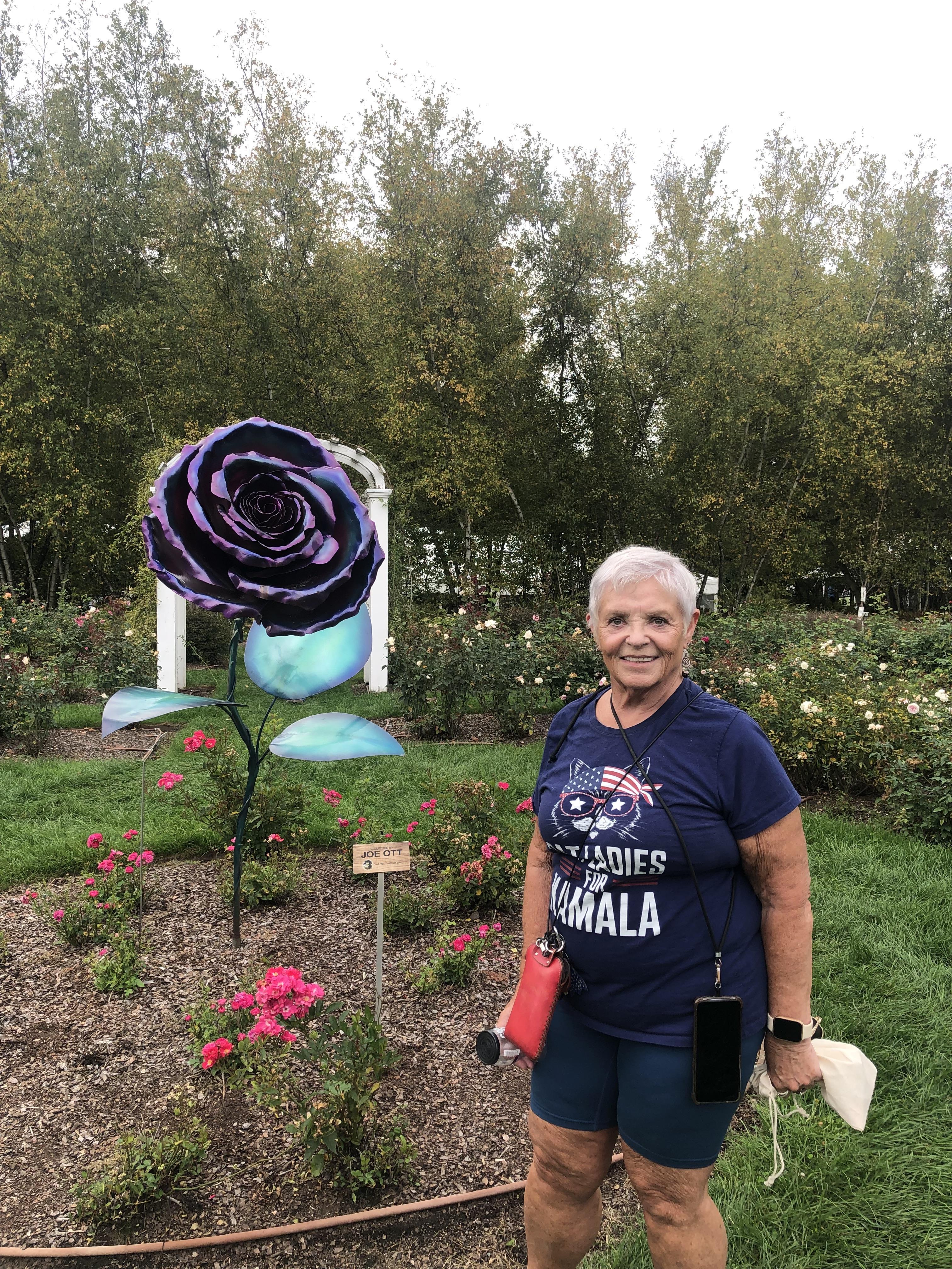 A woman standing in a garden with a purple rose