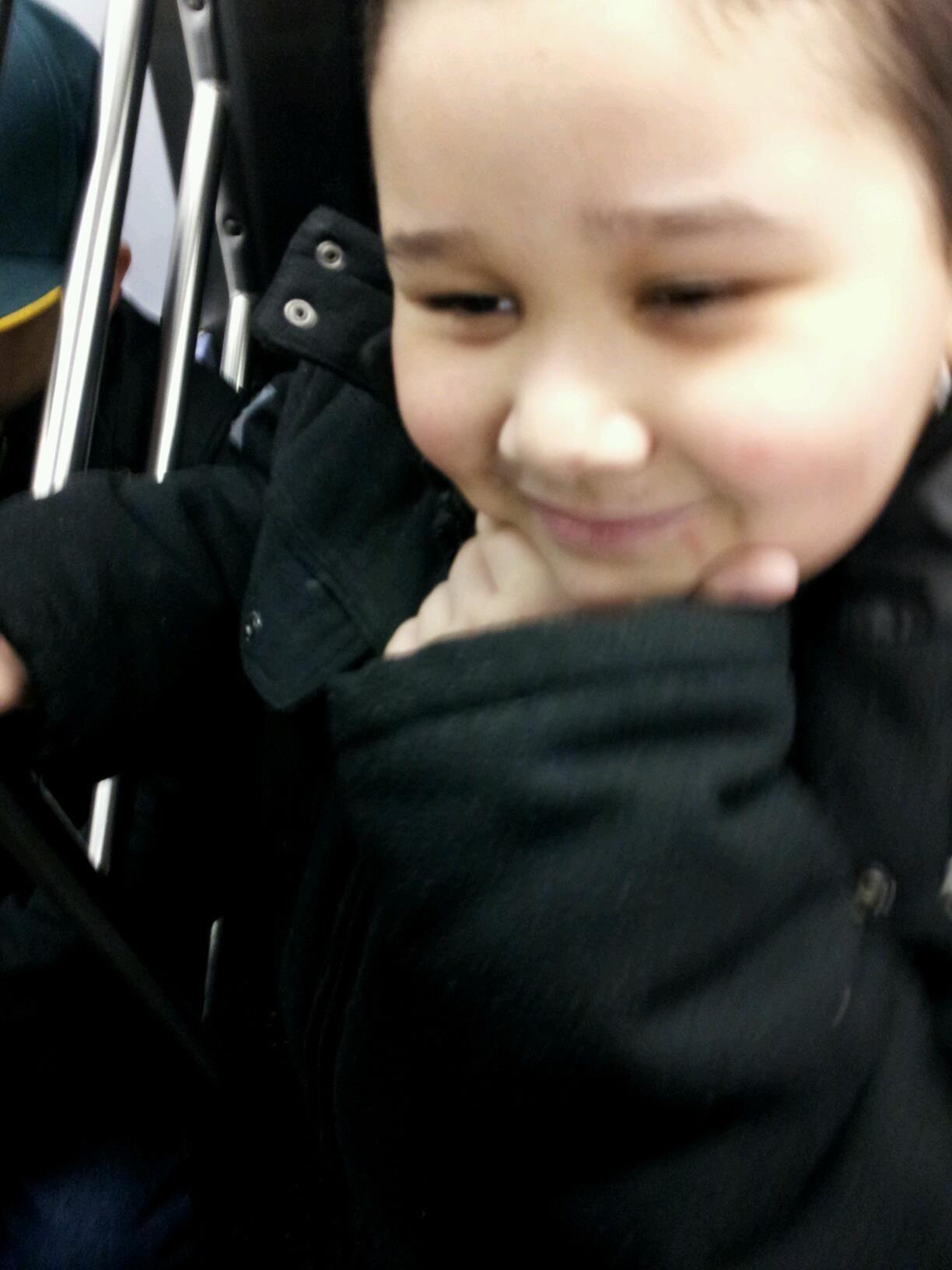 A child smiling with hand on chin