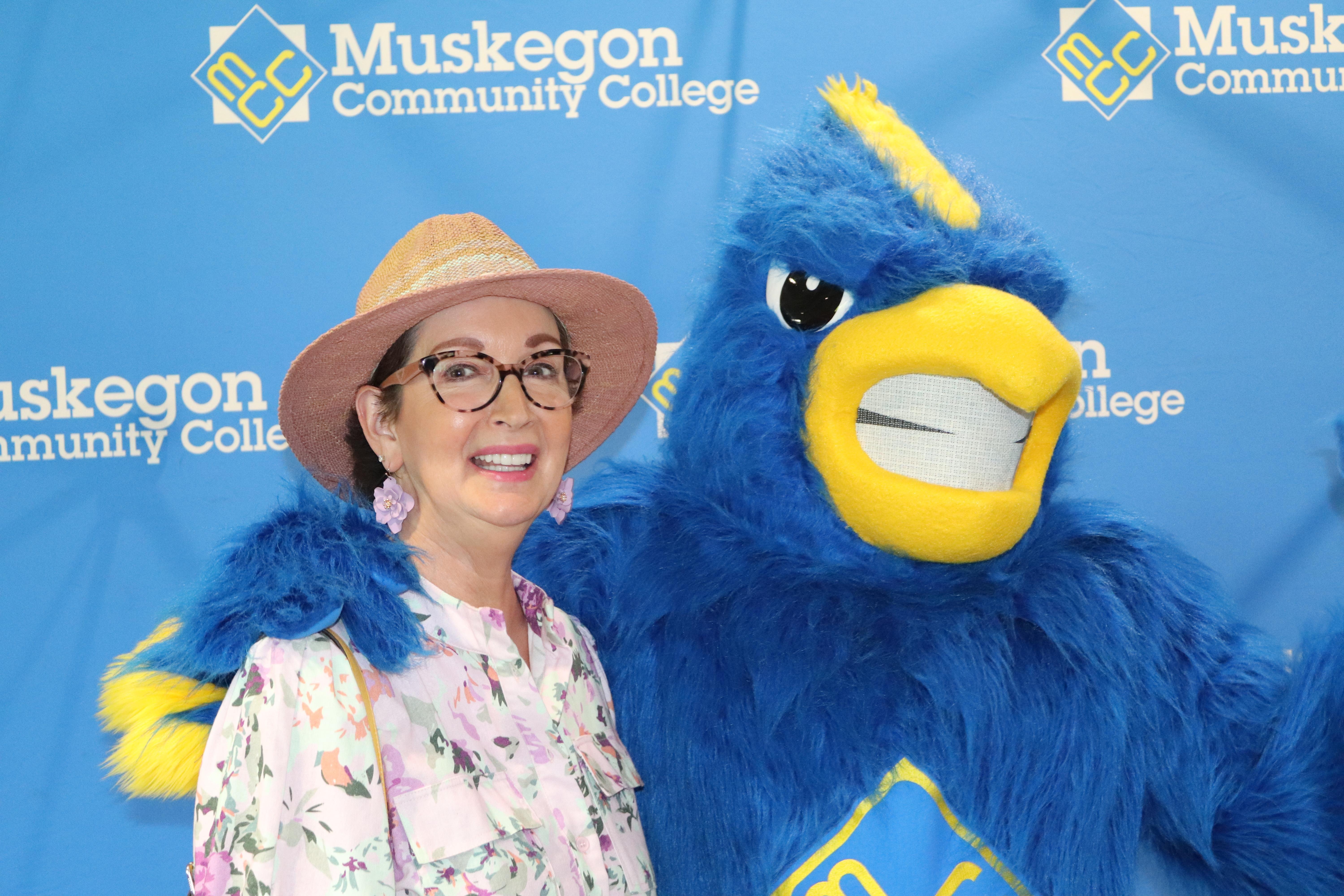 A woman standing next to a mascot