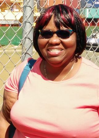 A woman smiling in front of a fence