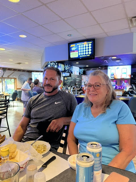 A man and woman sitting at a table with food and drinks