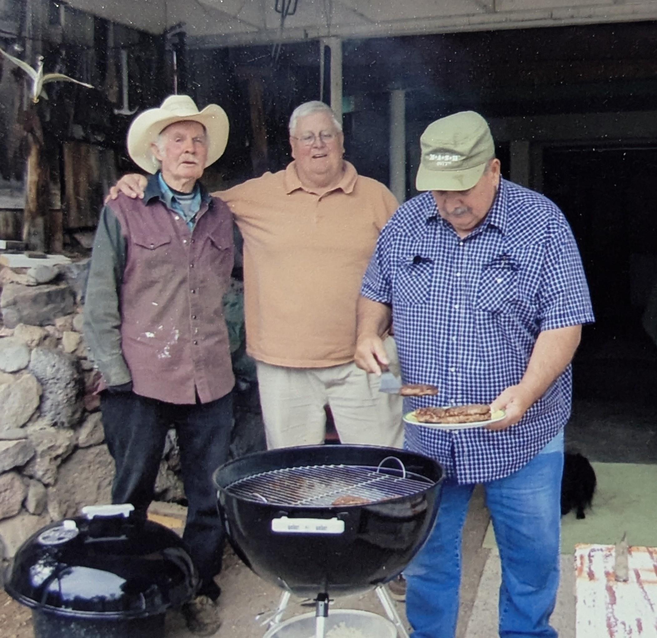 A group of men standing around a barbecue grill