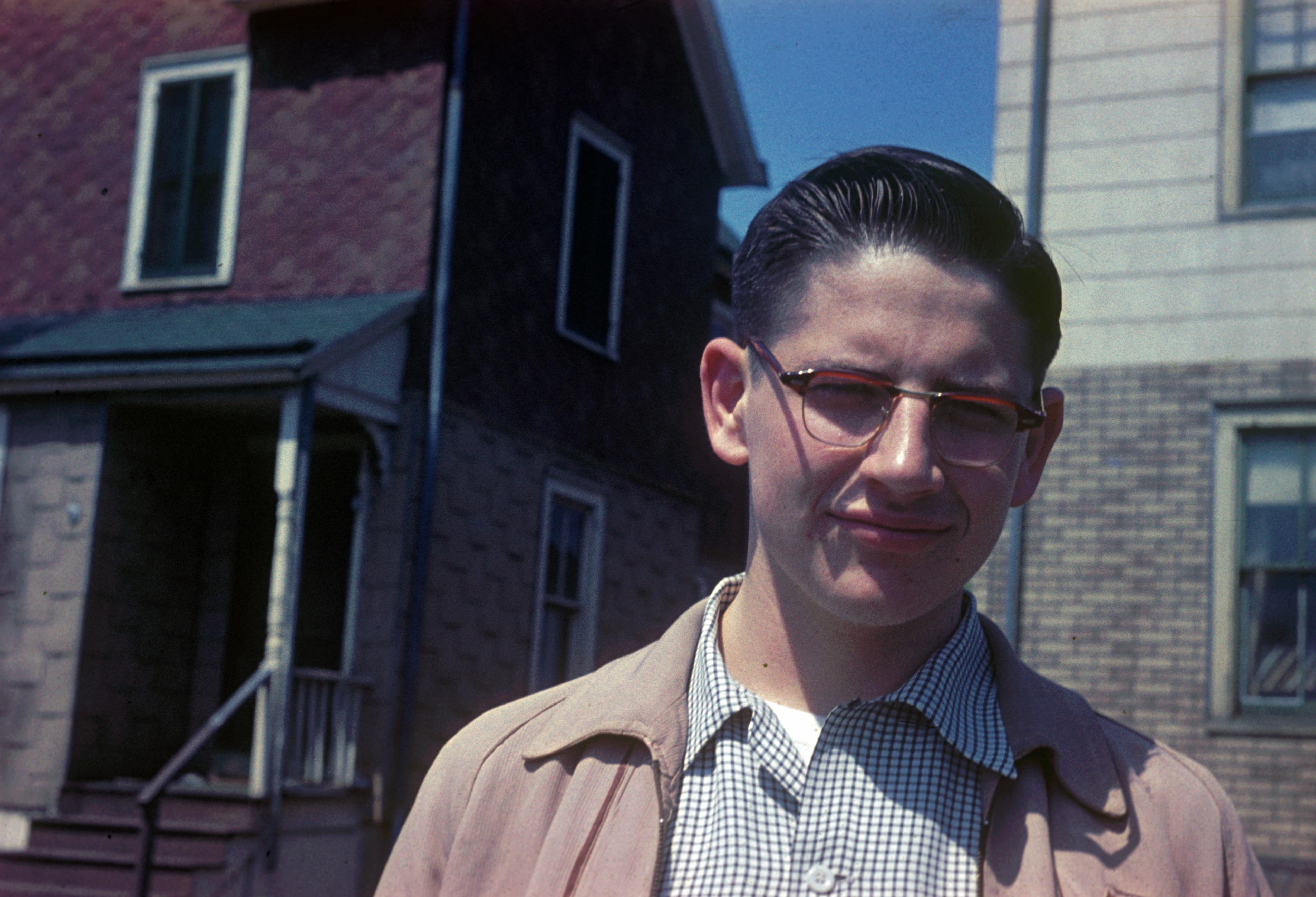 A man wearing glasses and a tan jacket