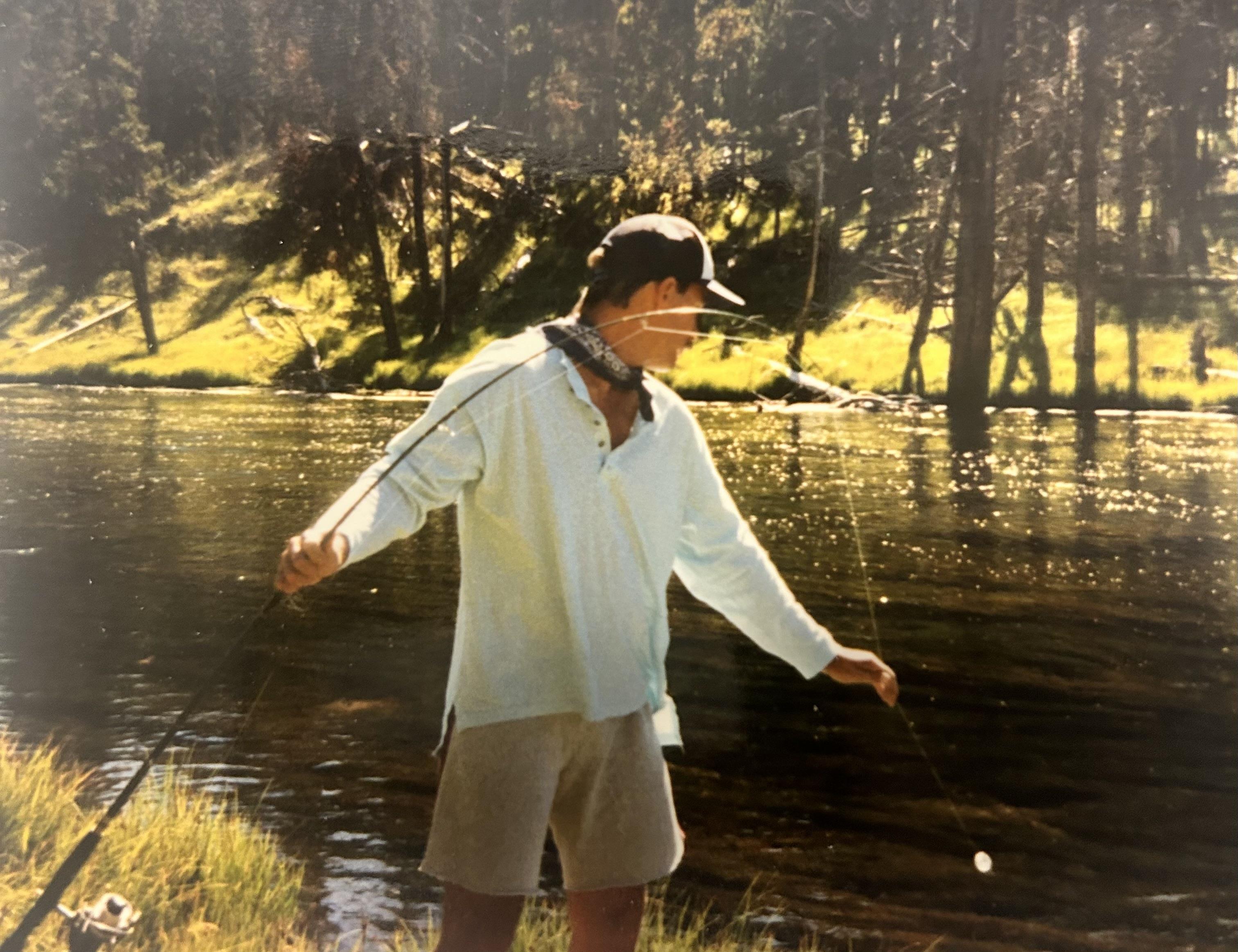 A man standing in a river holding a fishing rod