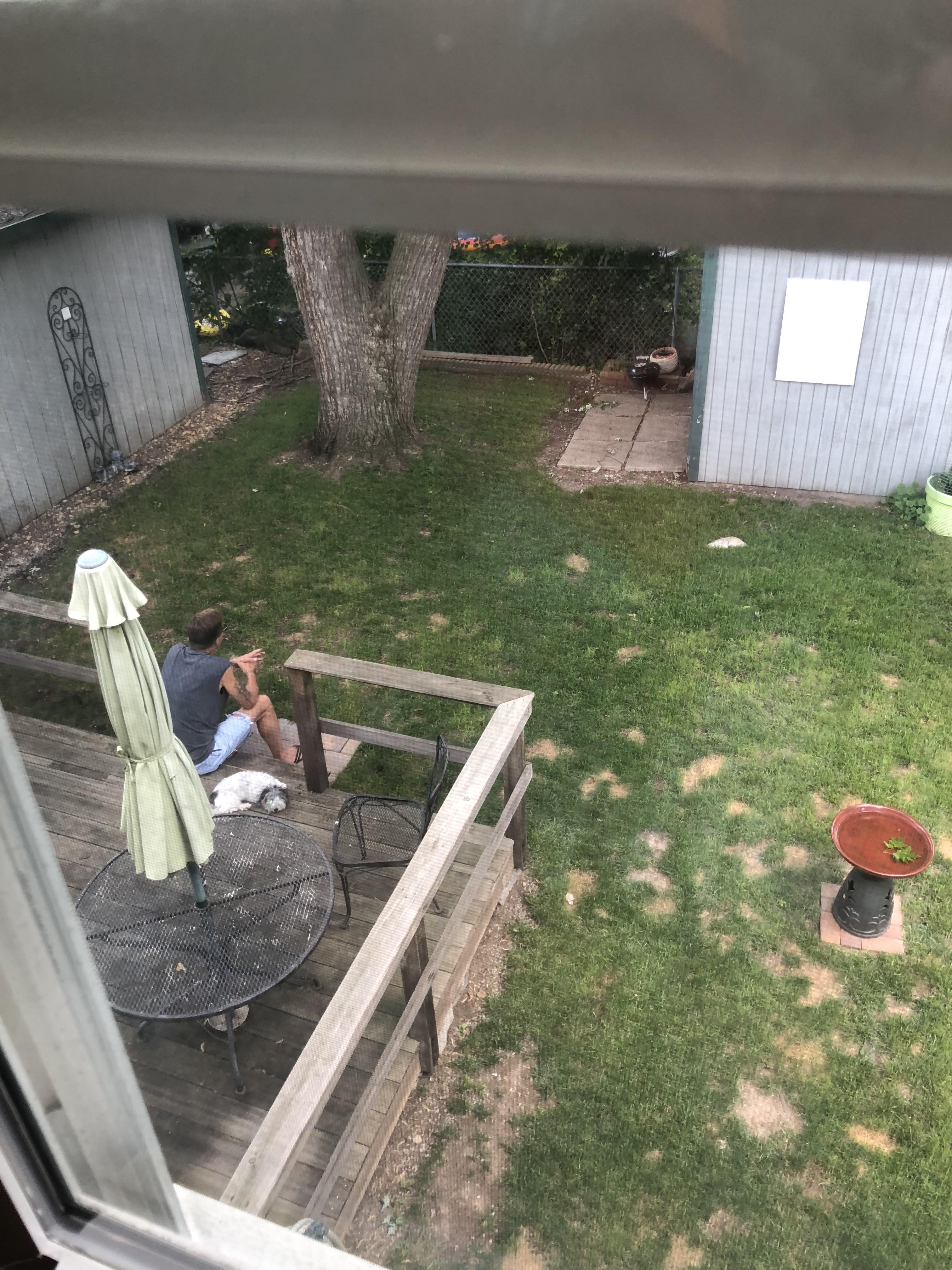 A man sitting on a deck with a dog on it