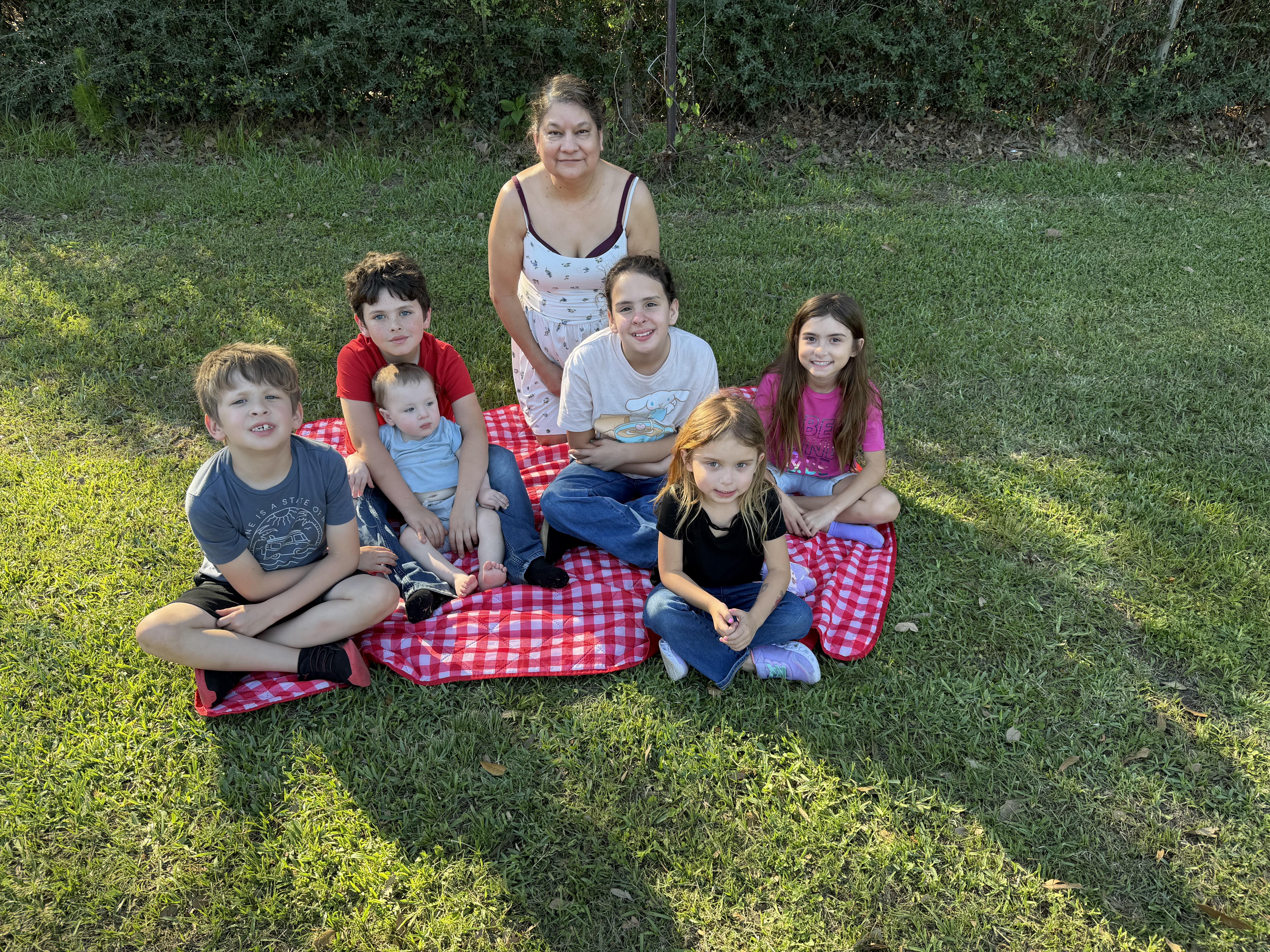 A group of people sitting on a blanket in a grassy area
