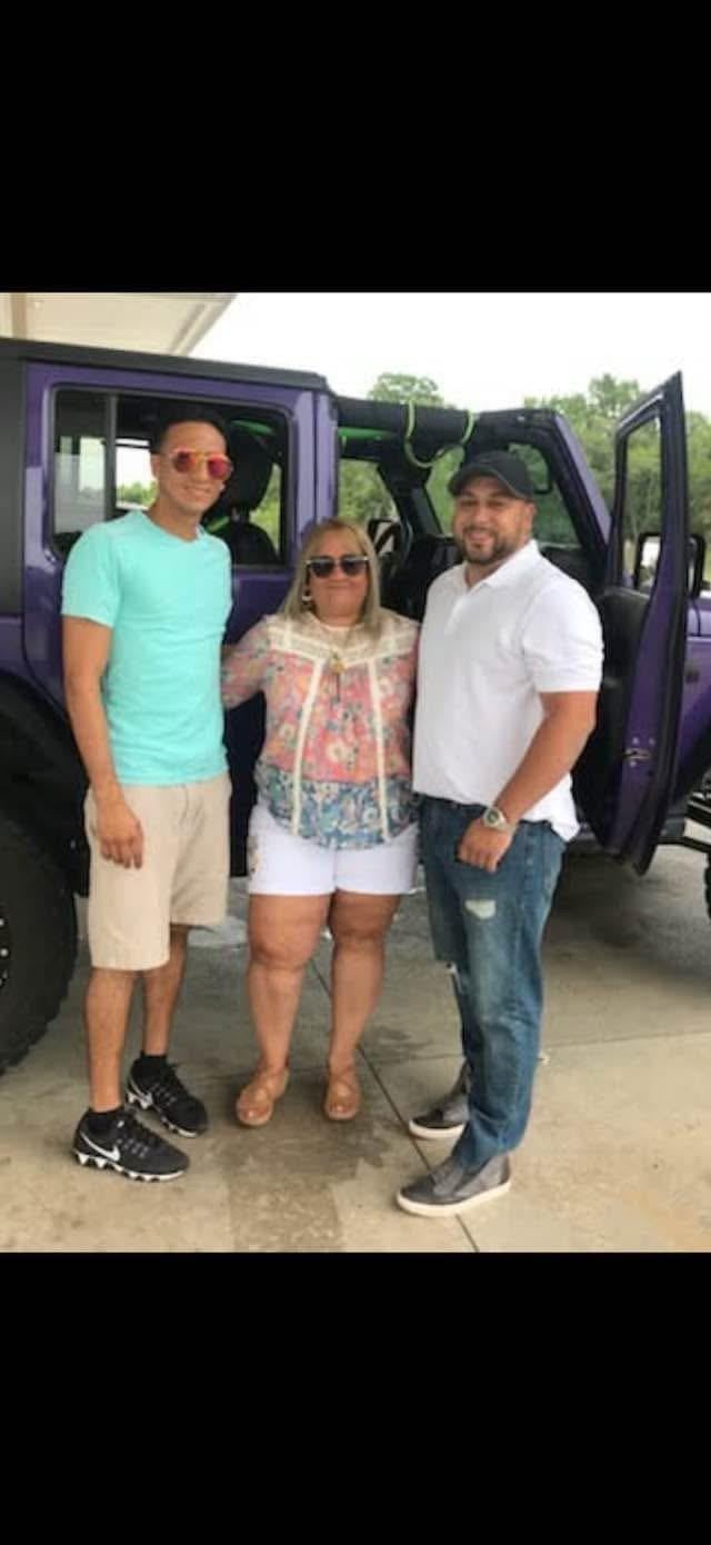 A group of people standing in front of a purple vehicle