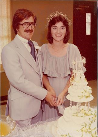 A man and woman standing next to a cake