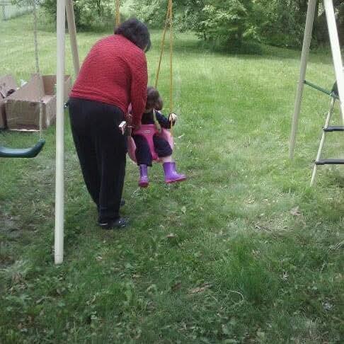 A woman pushing a child on a swing