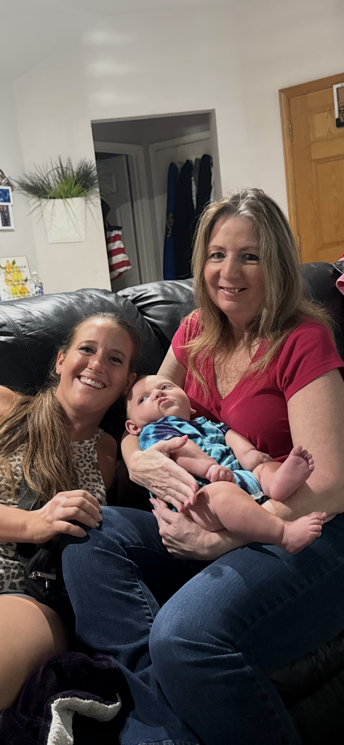 A group of women sitting on a couch holding a baby