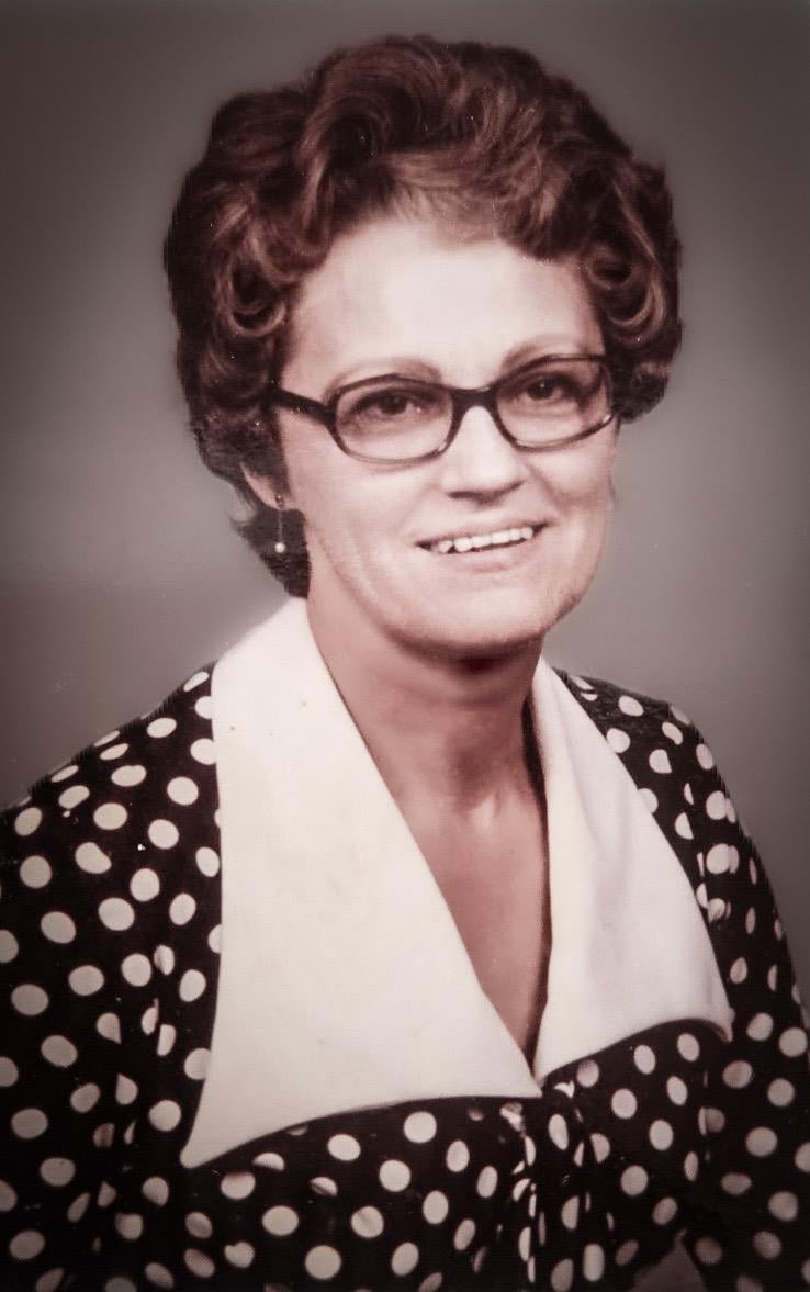 A woman wearing glasses and a polka dot jacket