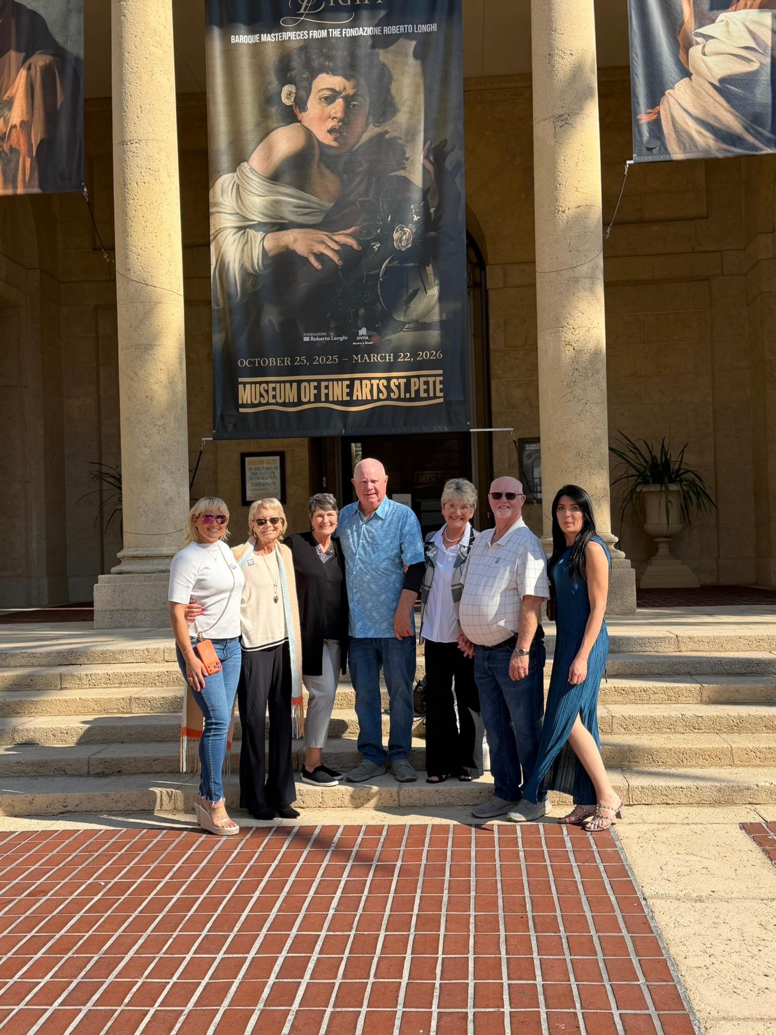 A group of people posing for a photo in front of a museum