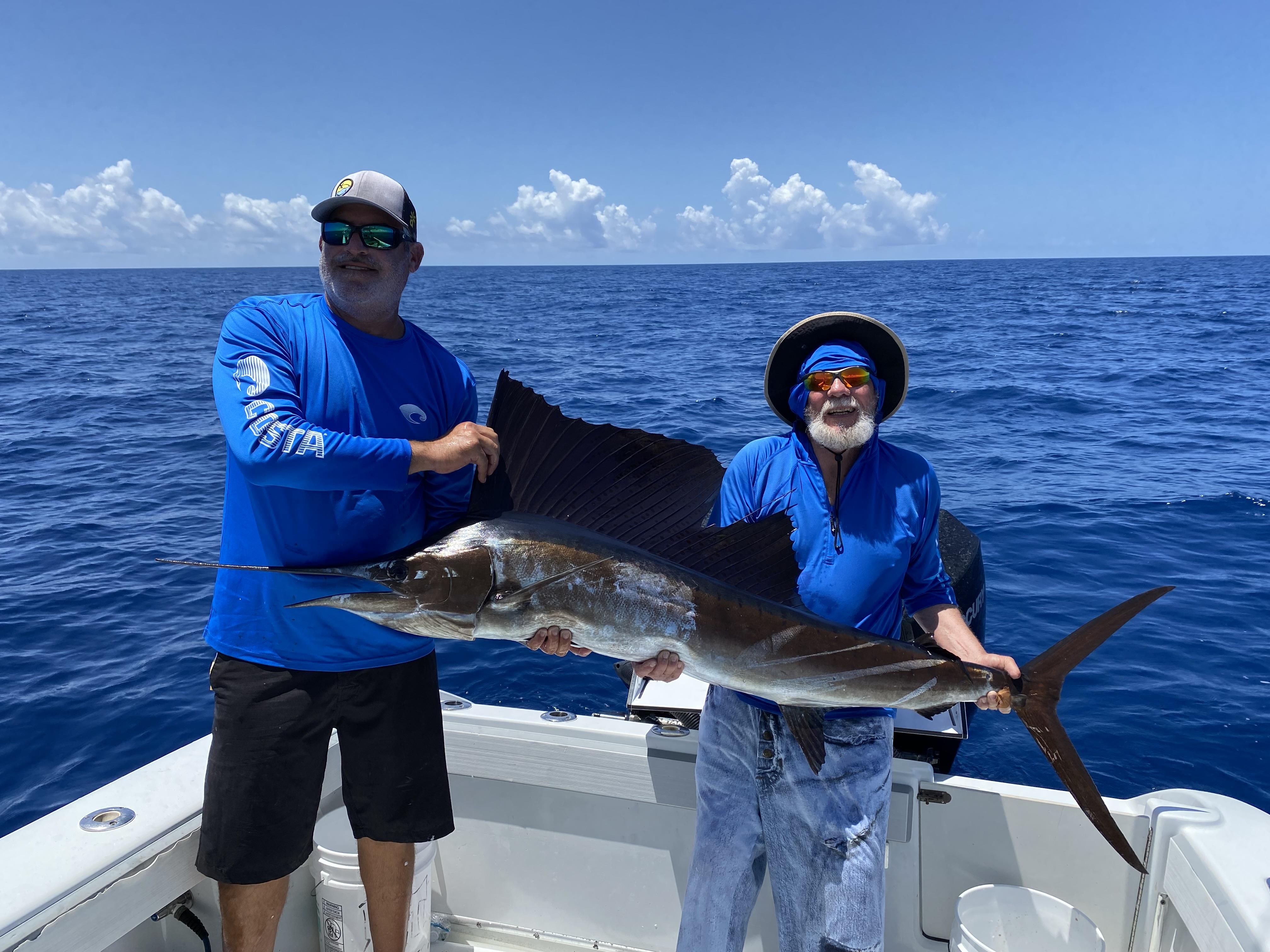 Two men holding a swordfish on a boat