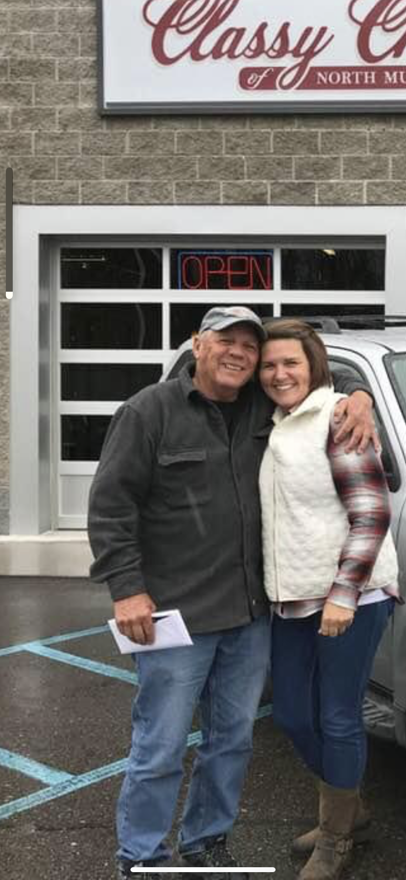 A man and woman standing in front of a car