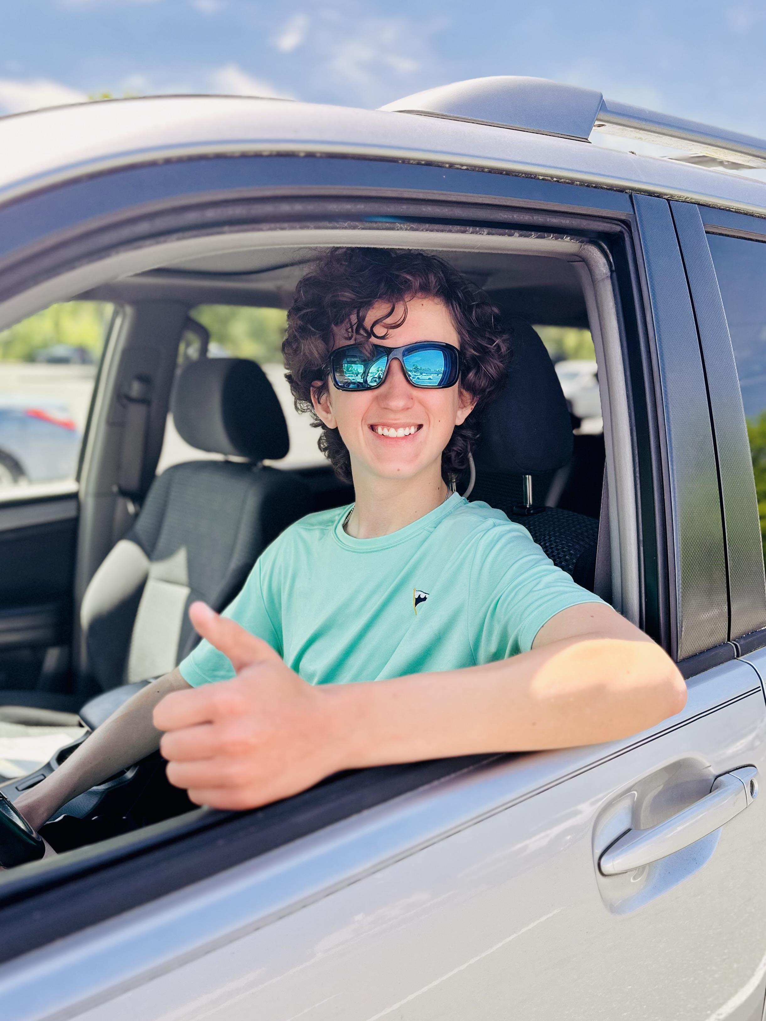 A man in a car with his thumb up