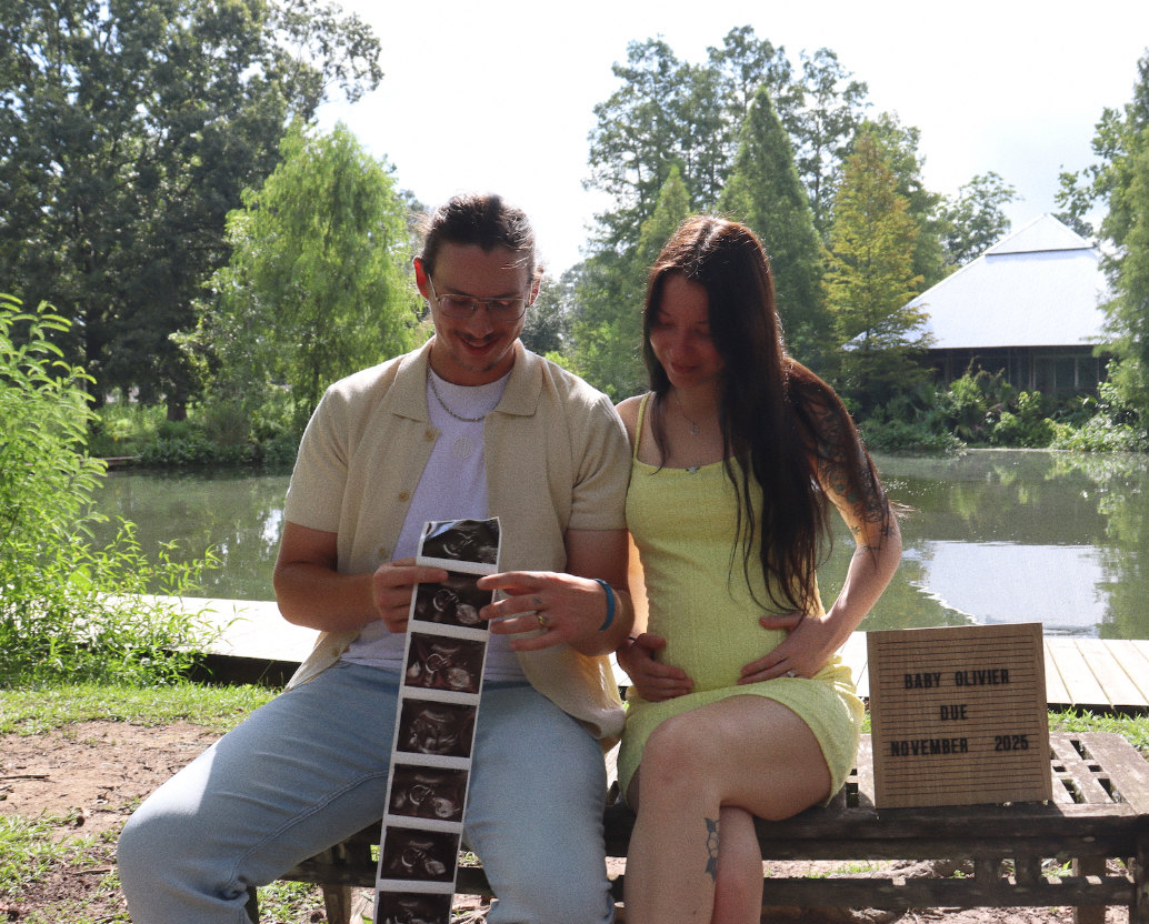 A man and woman sitting on a bench looking at an ultrasound picture