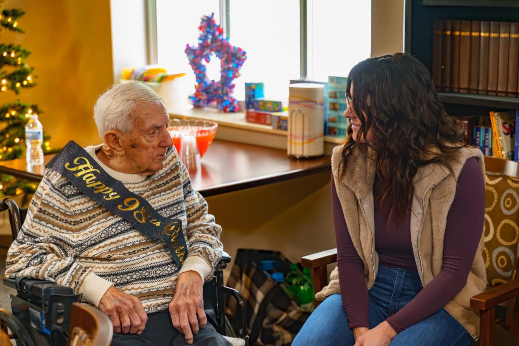 A woman sitting in a chair with an old man in a wheelchair