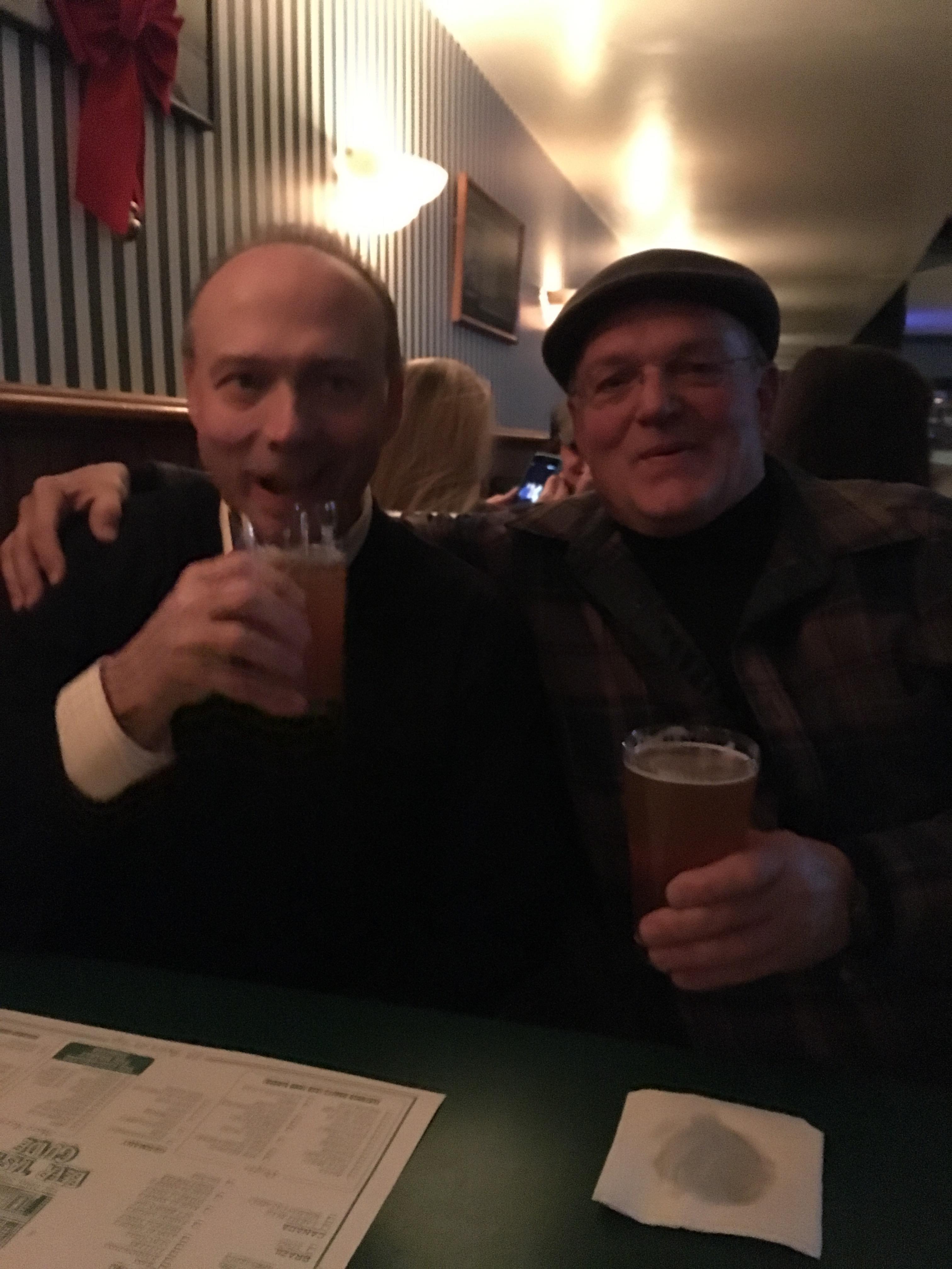 Two men sitting at a table holding drinks