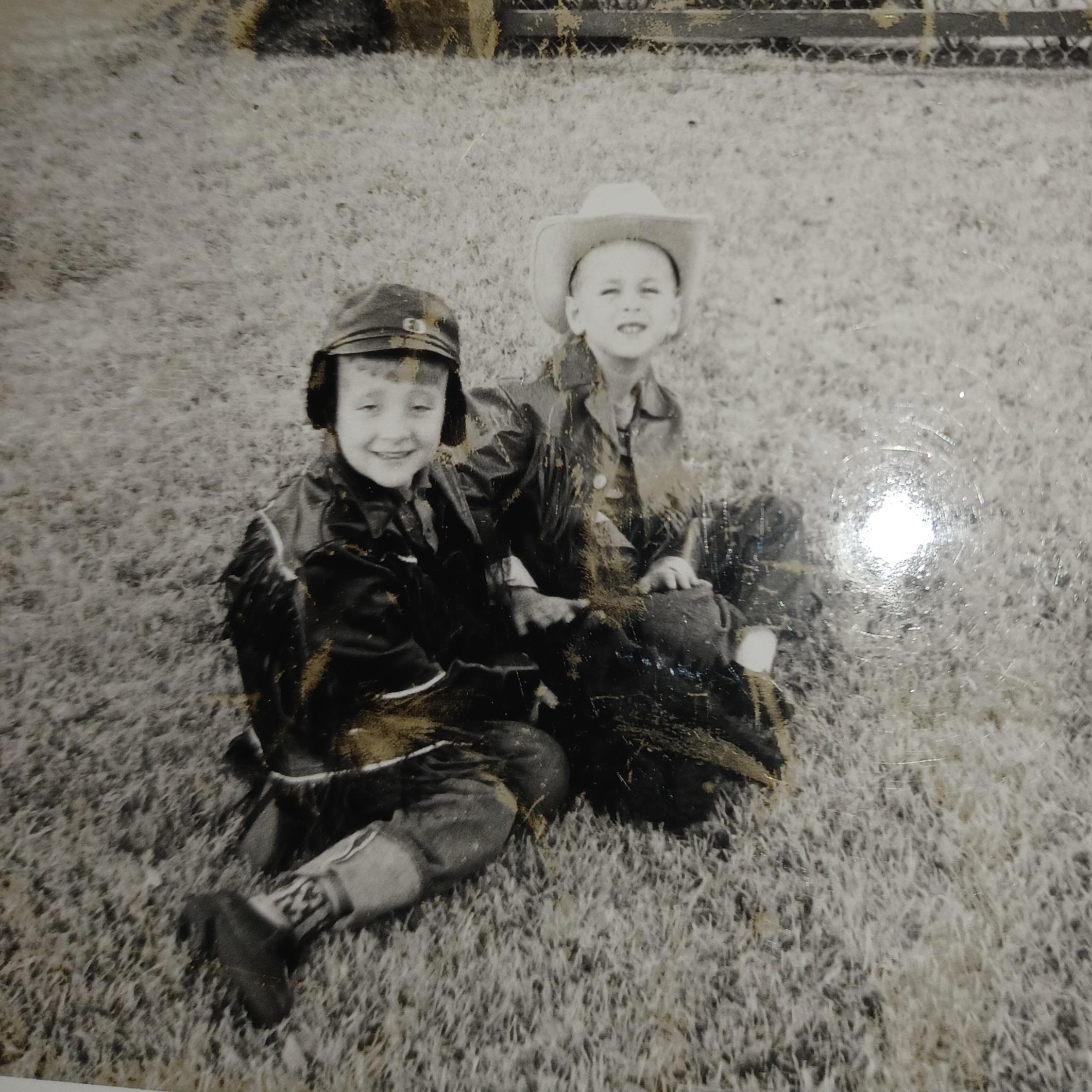A couple of boys sitting on grass