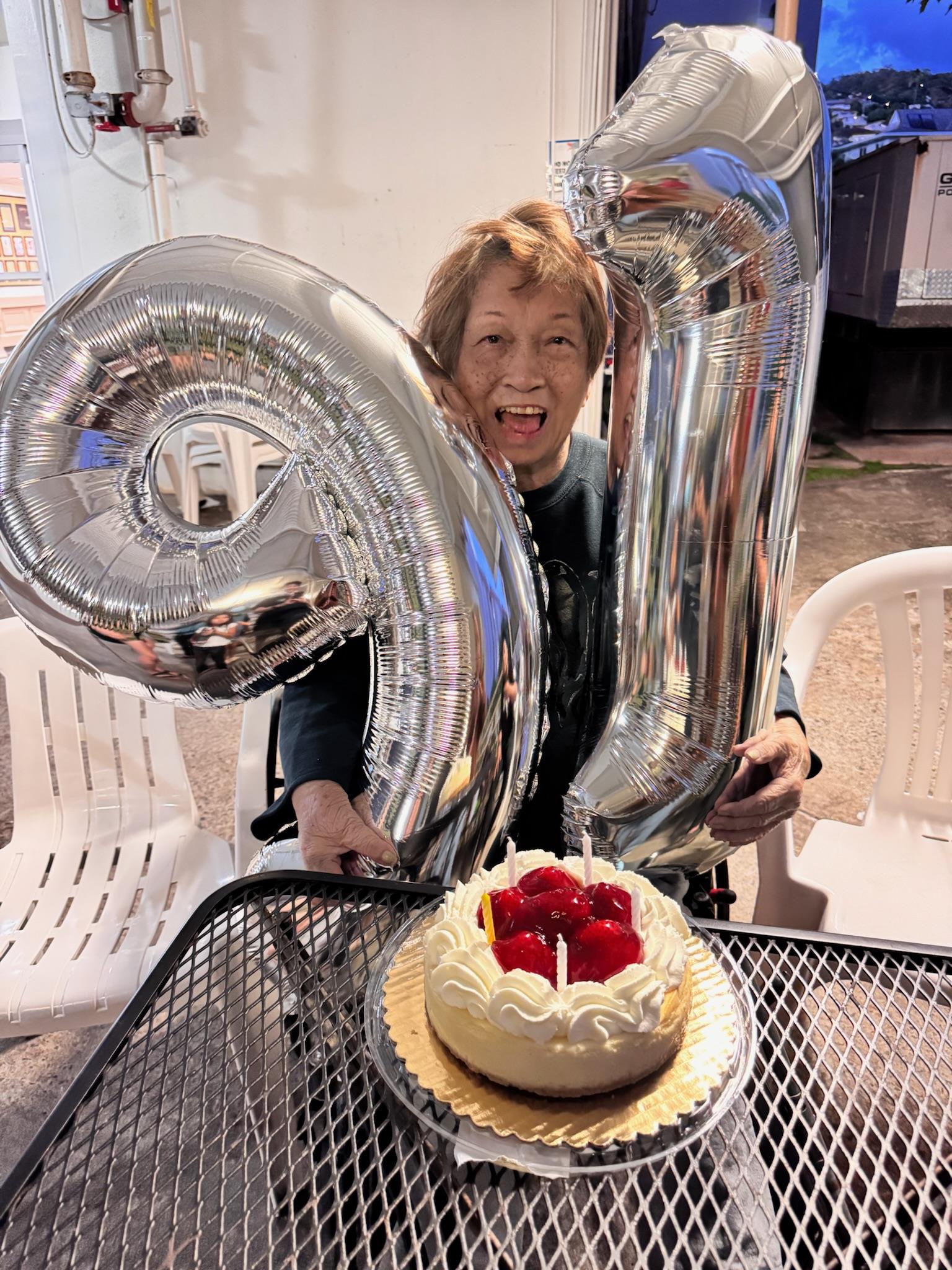 A woman holding a silver balloon and a cake
