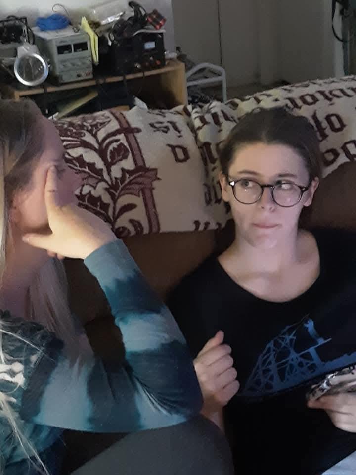 A woman sitting on a couch with another woman on her face