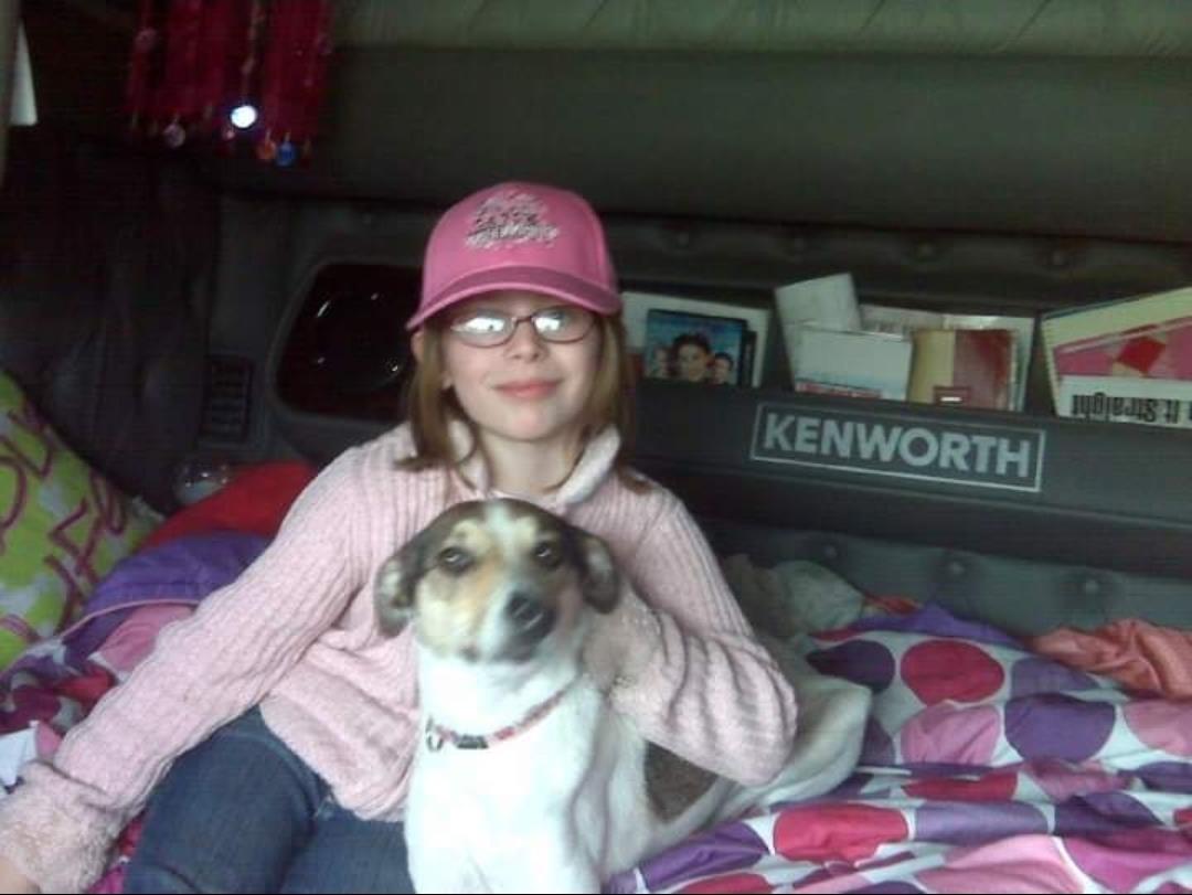 A girl sitting on a bed with a dog
