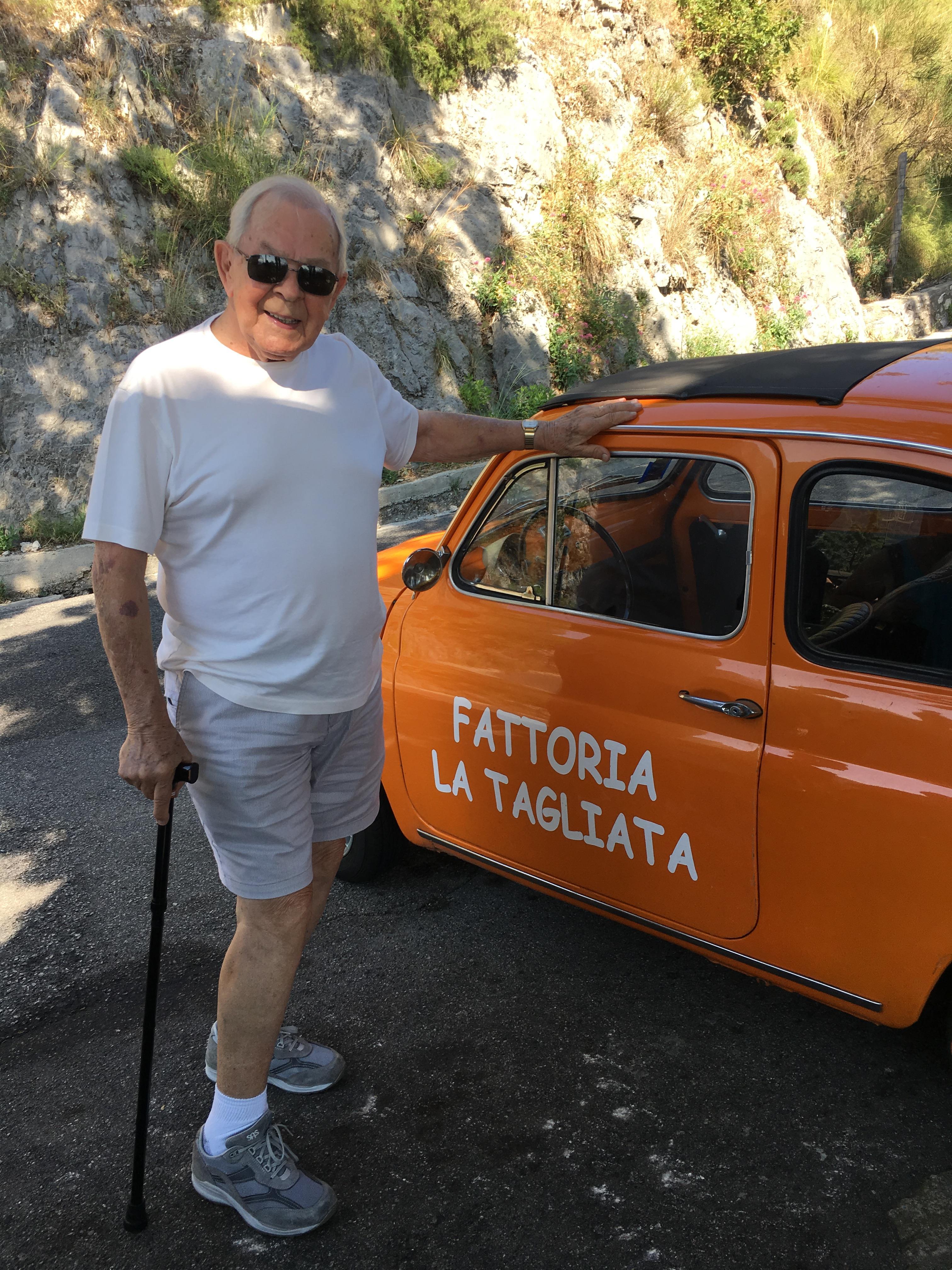 A man standing next to an orange car