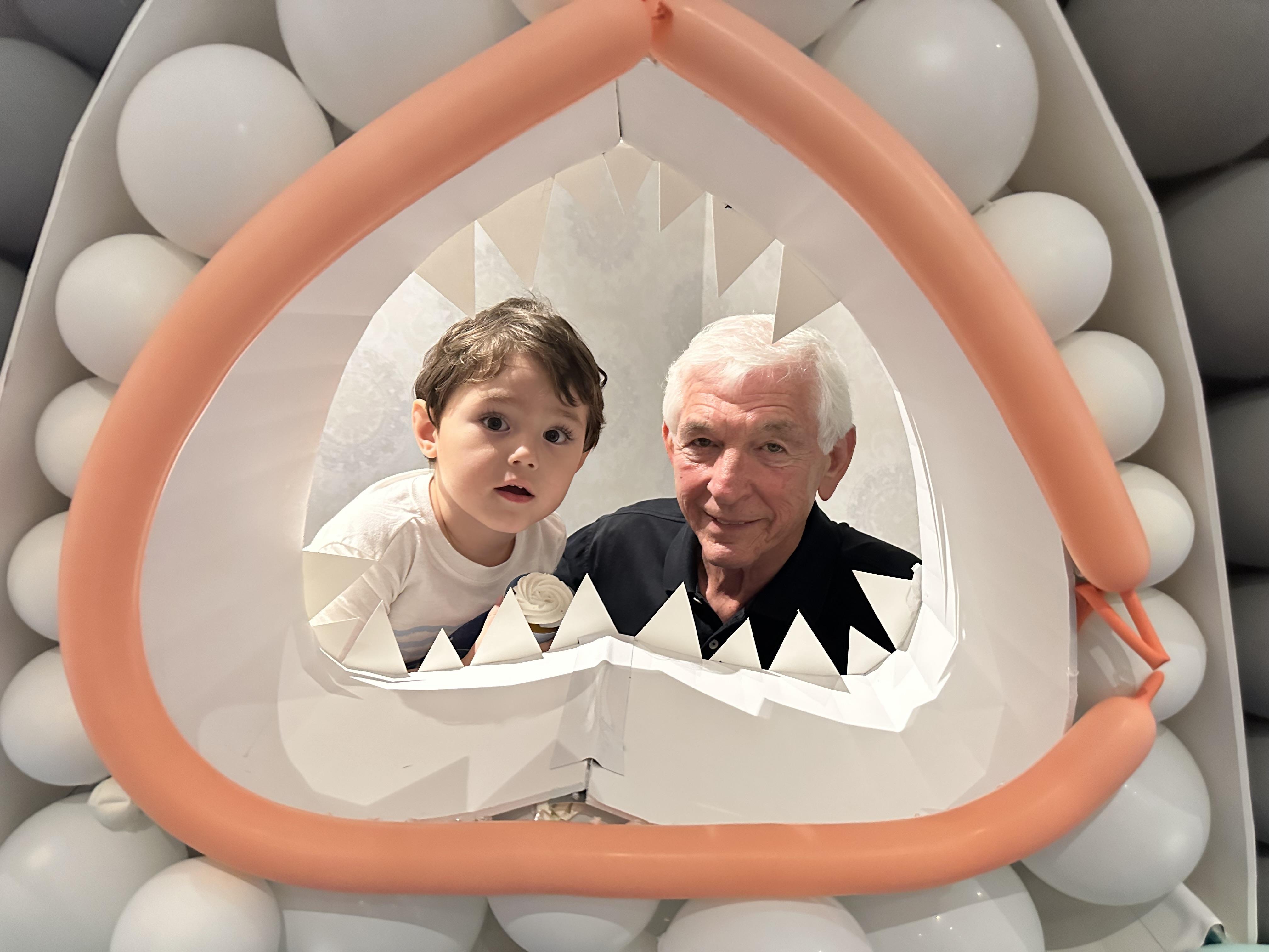 A man and boy looking through a shark shaped object