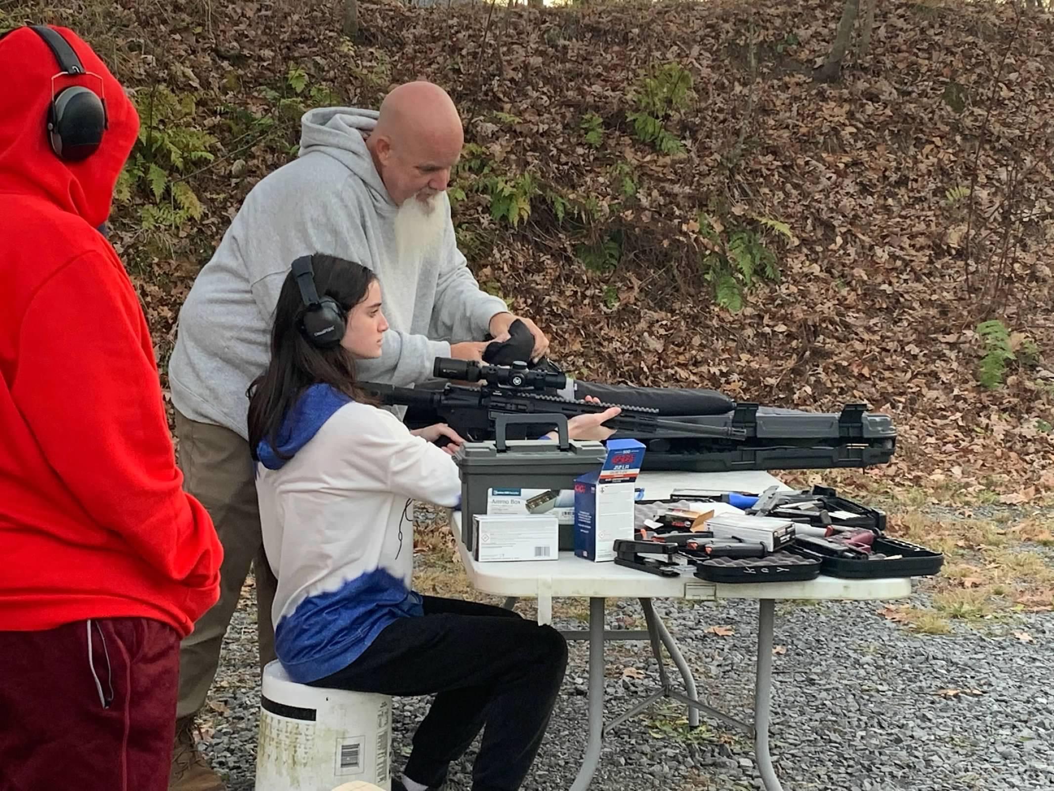 A man and woman sitting at a table with guns