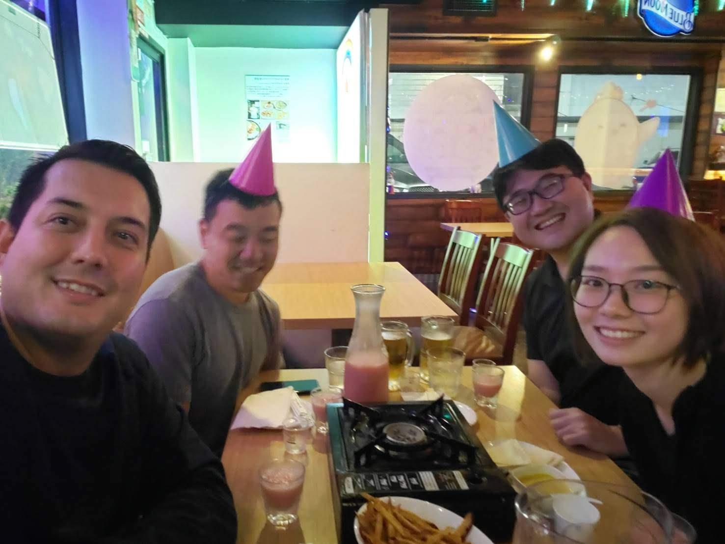 A group of people sitting at a table with food and drinks