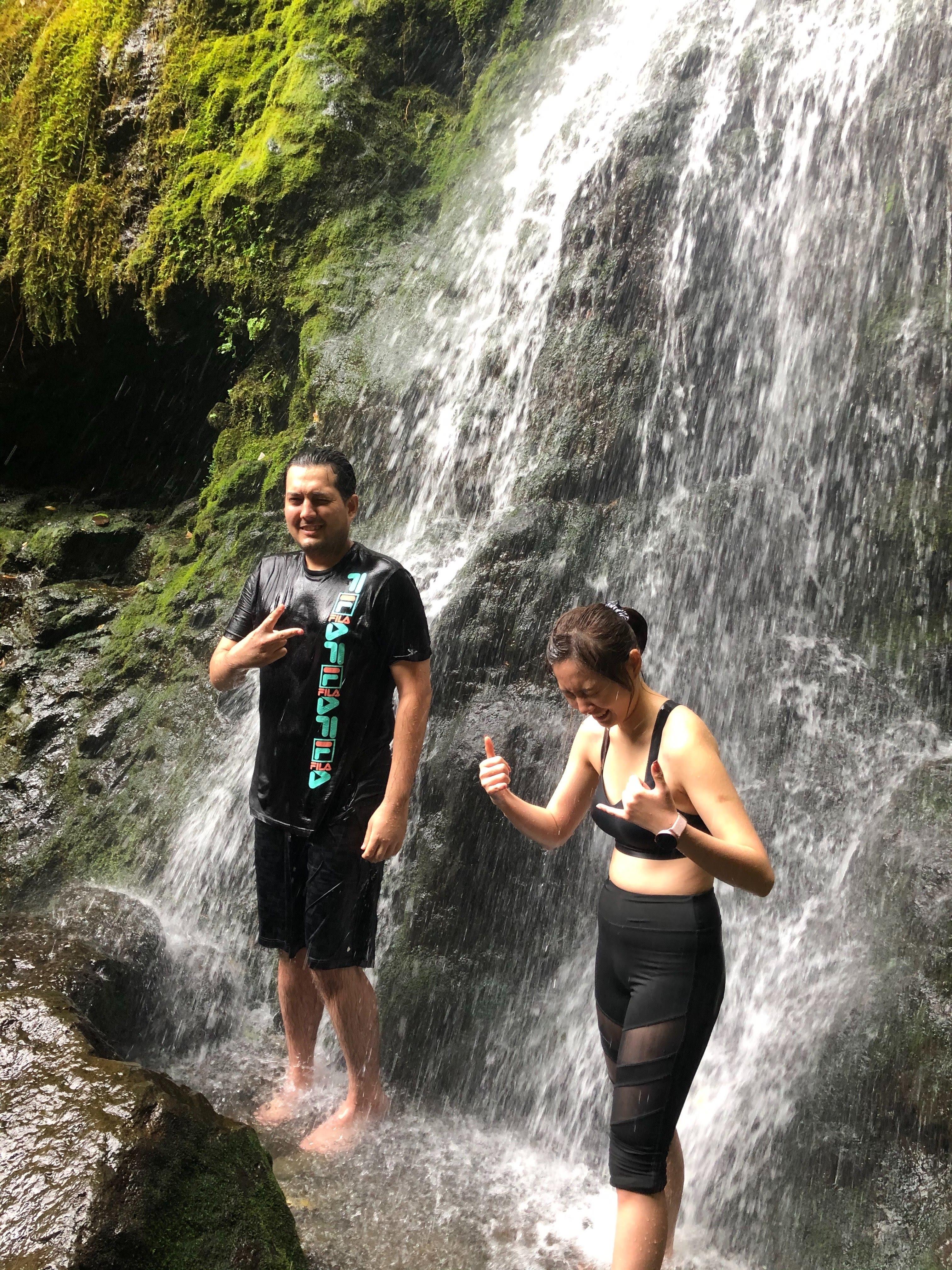 A man and woman standing in front of a waterfall