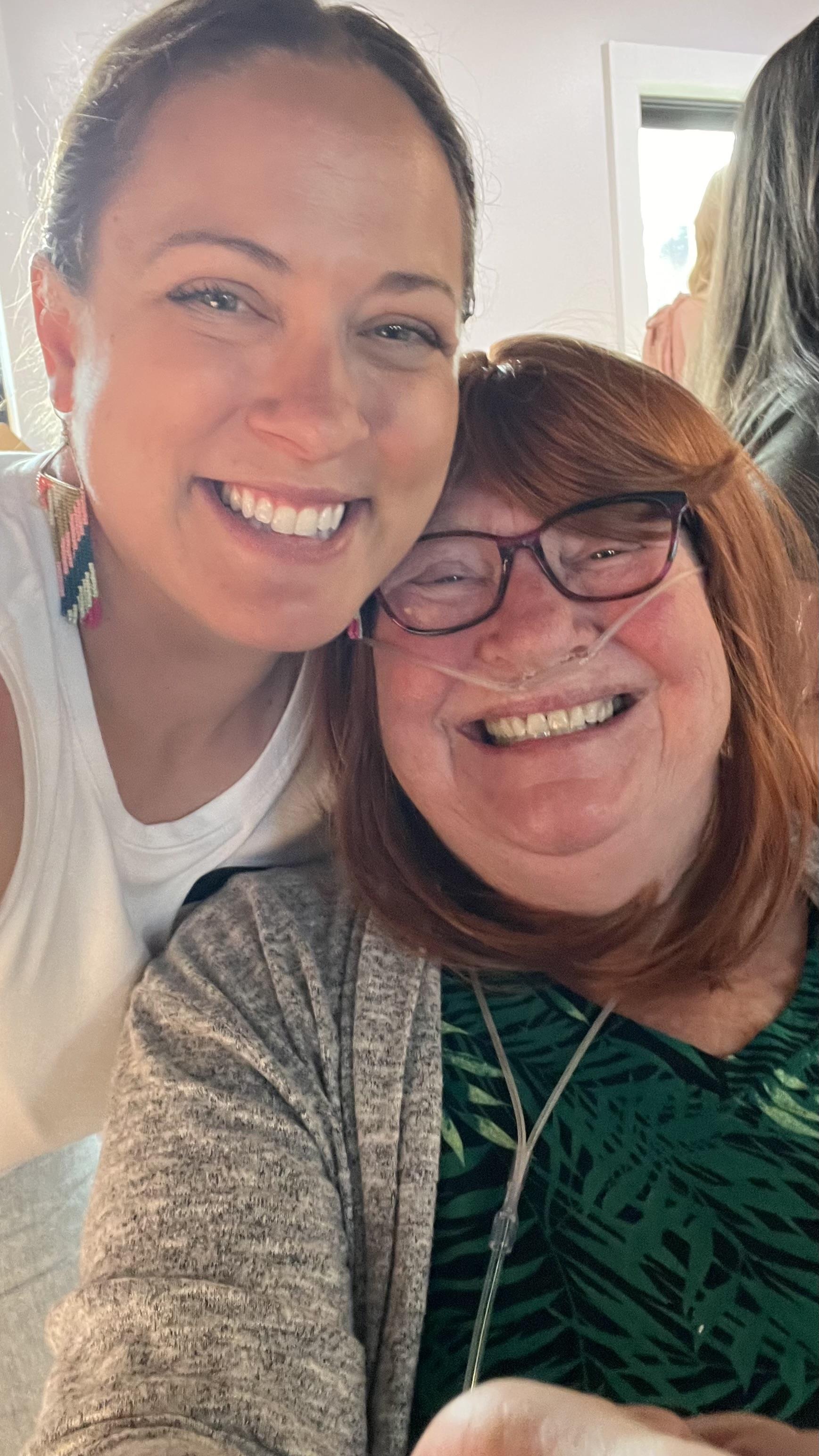 A woman smiling with her arm around another woman