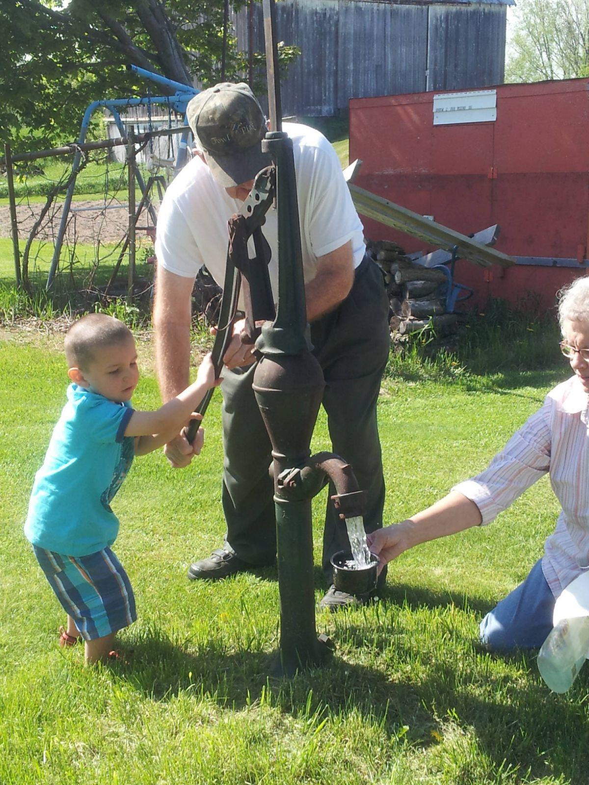 A man and child standing next to a water pump