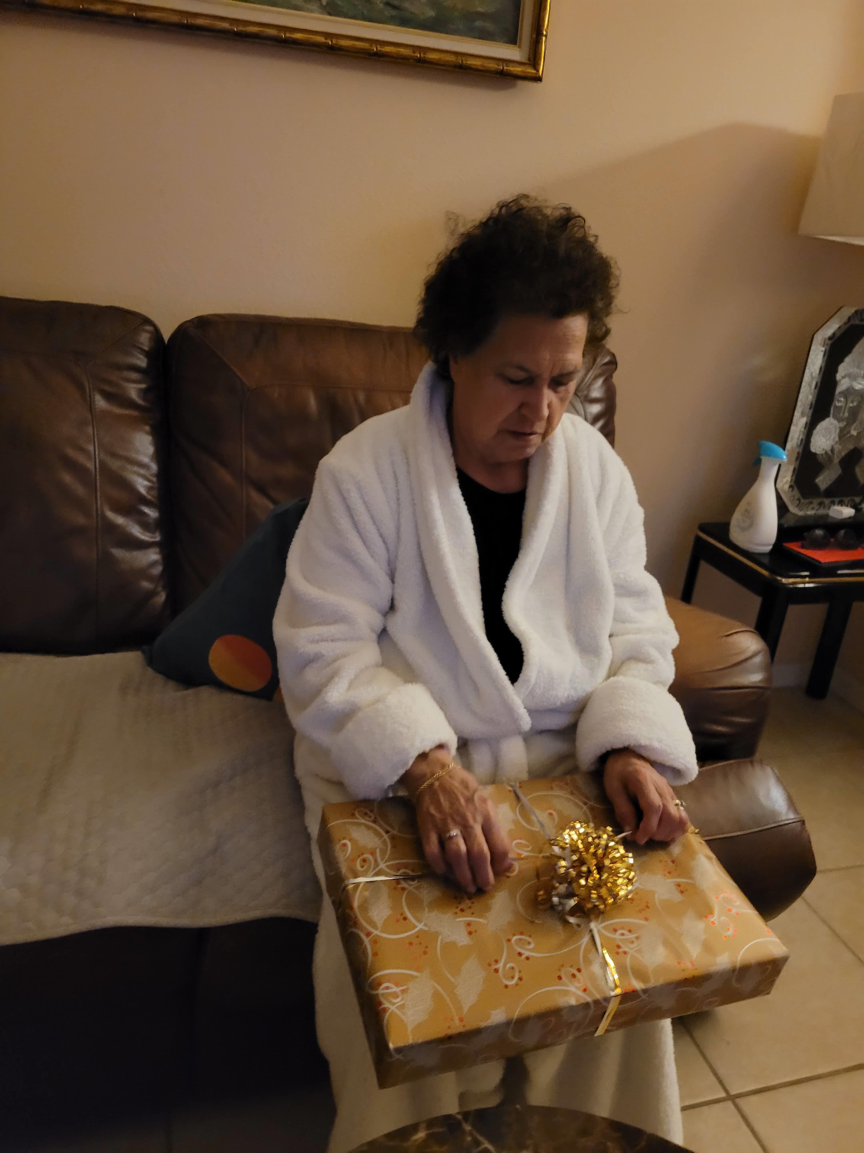 A woman sitting on a couch opening a present