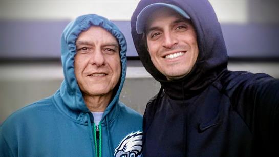 Two men wearing hoodies and standing together