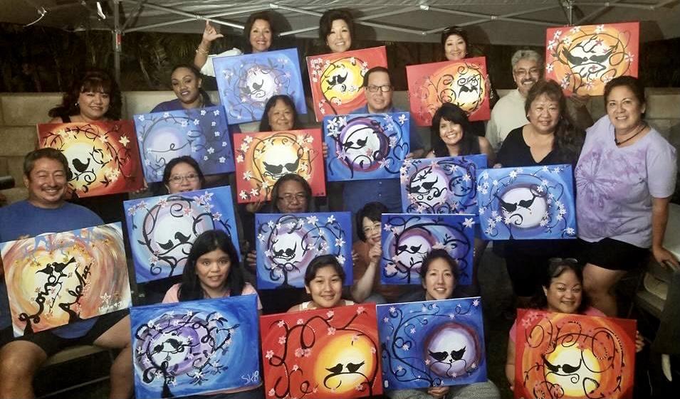 A group of people holding up paintings