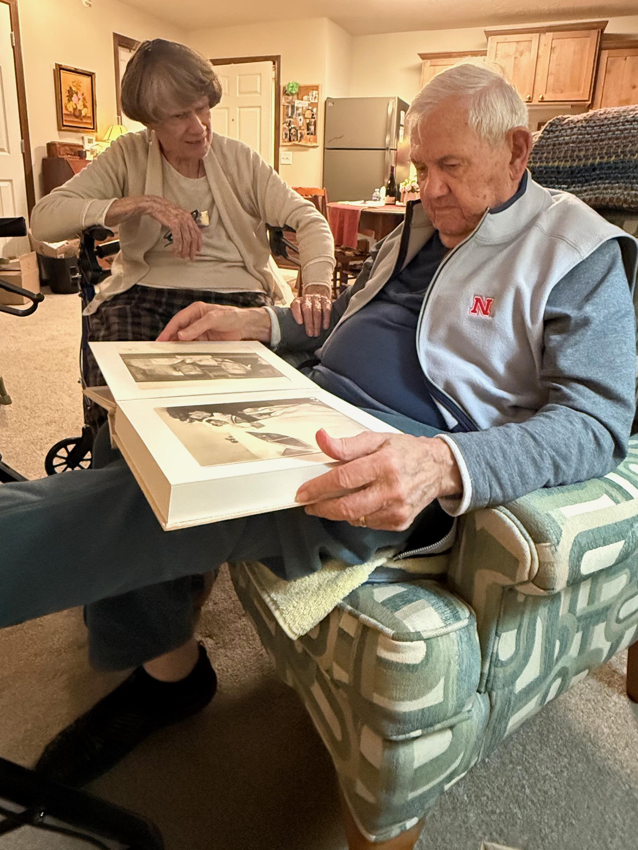 A man and woman sitting in a chair looking at a book