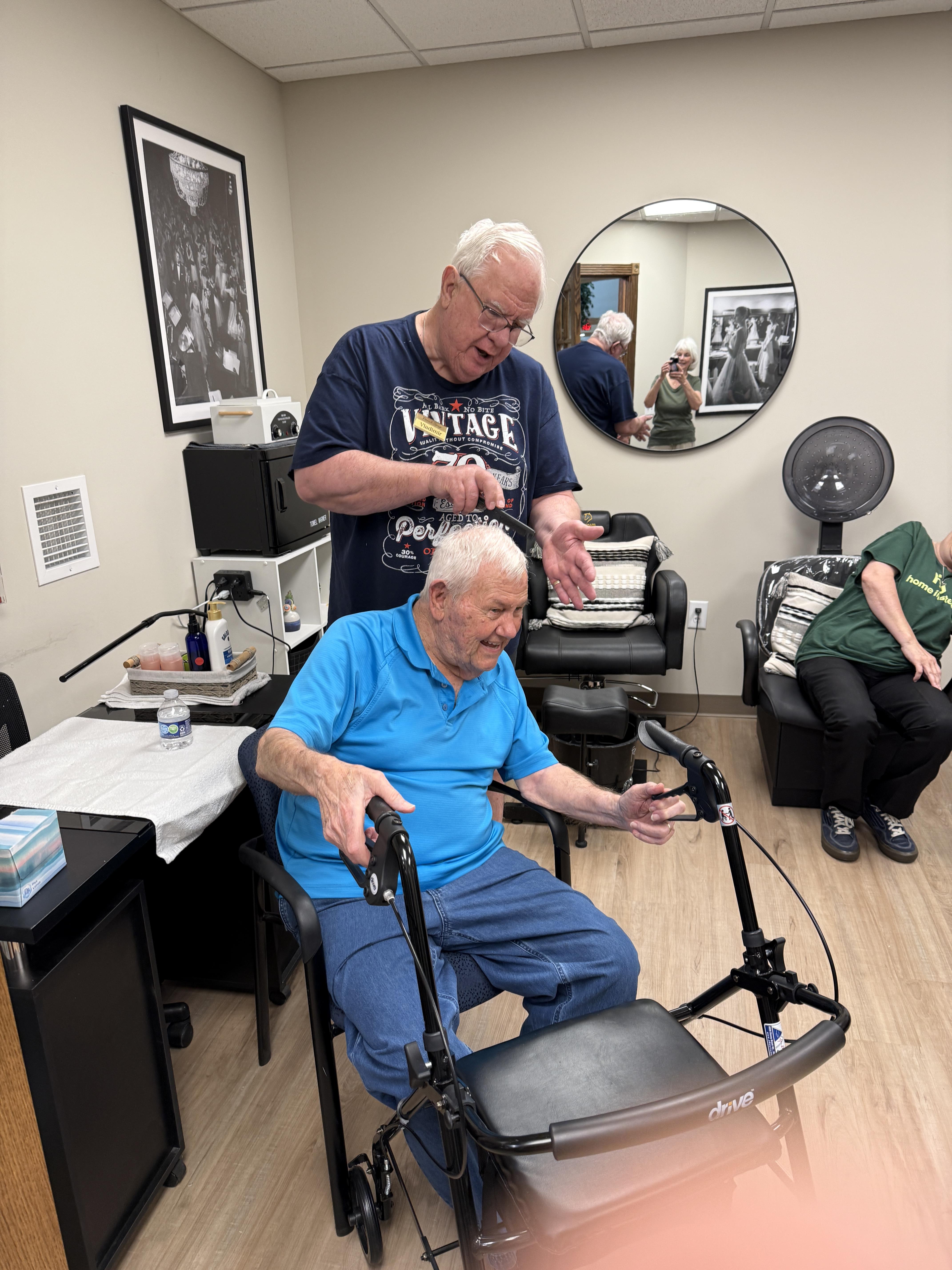 A man sitting in a wheelchair with a man in the back