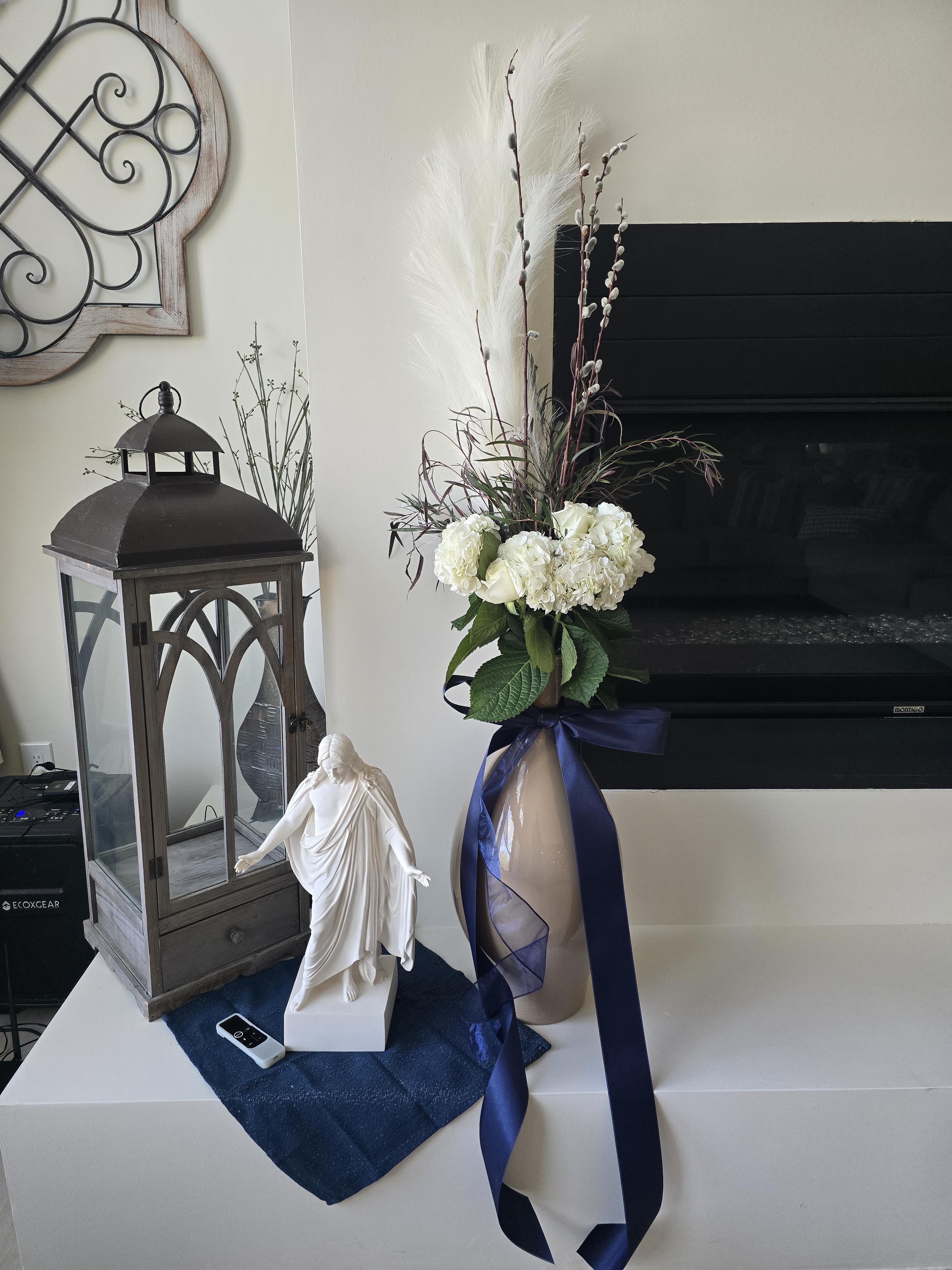 A vase with flowers and a statue on a white table
