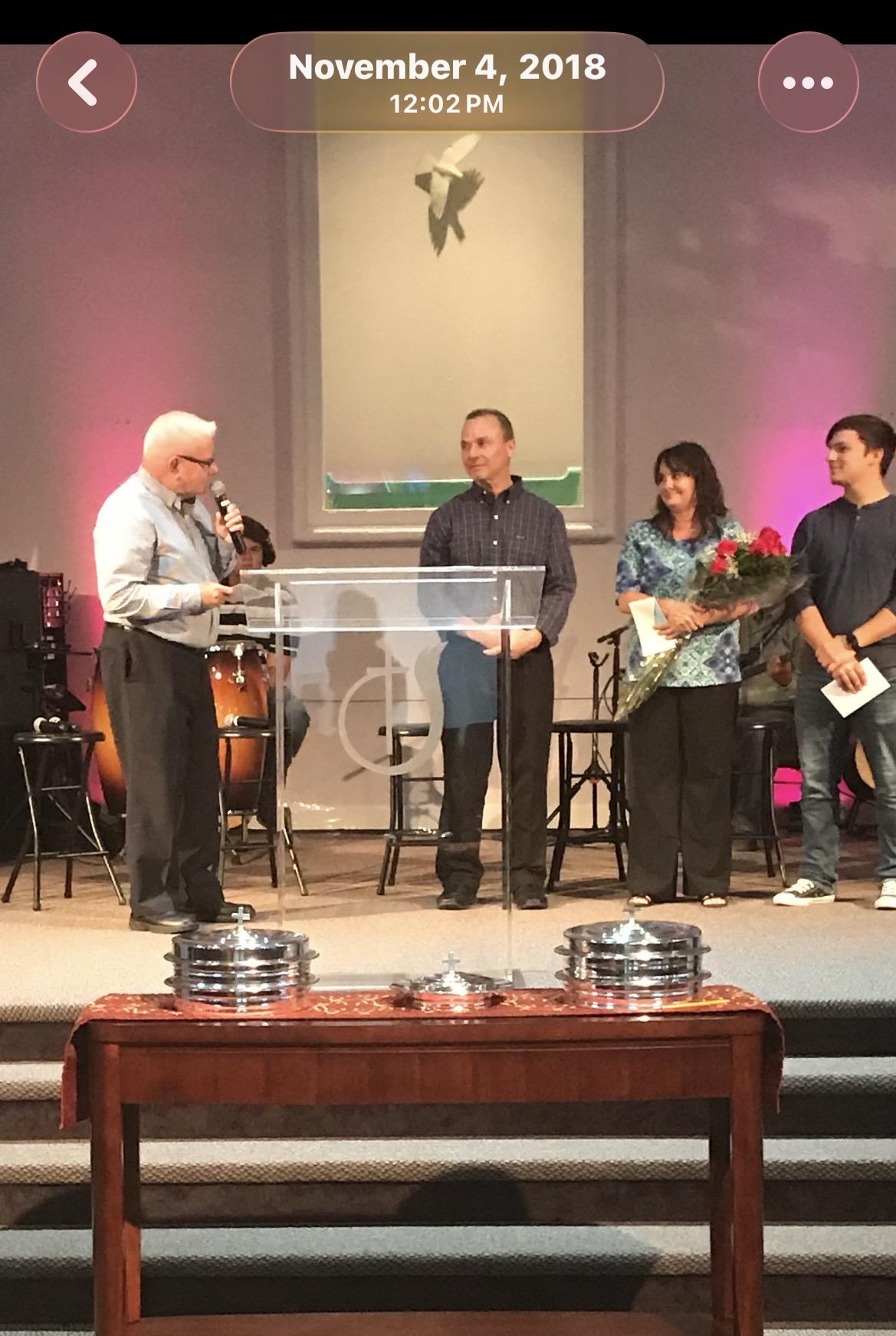 A man standing on a stage with a microphone and people around him