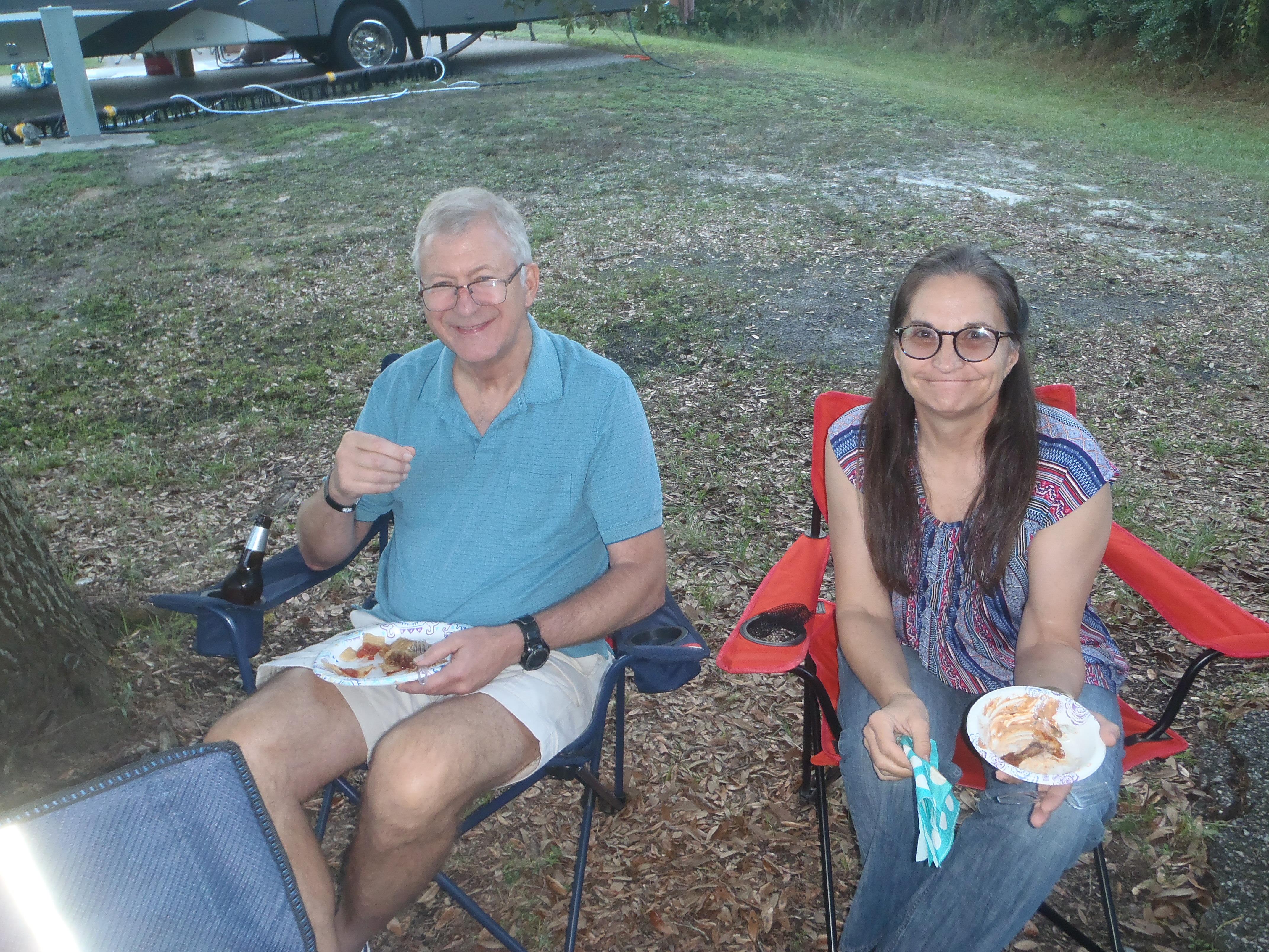A man and woman sitting in chairs eating food