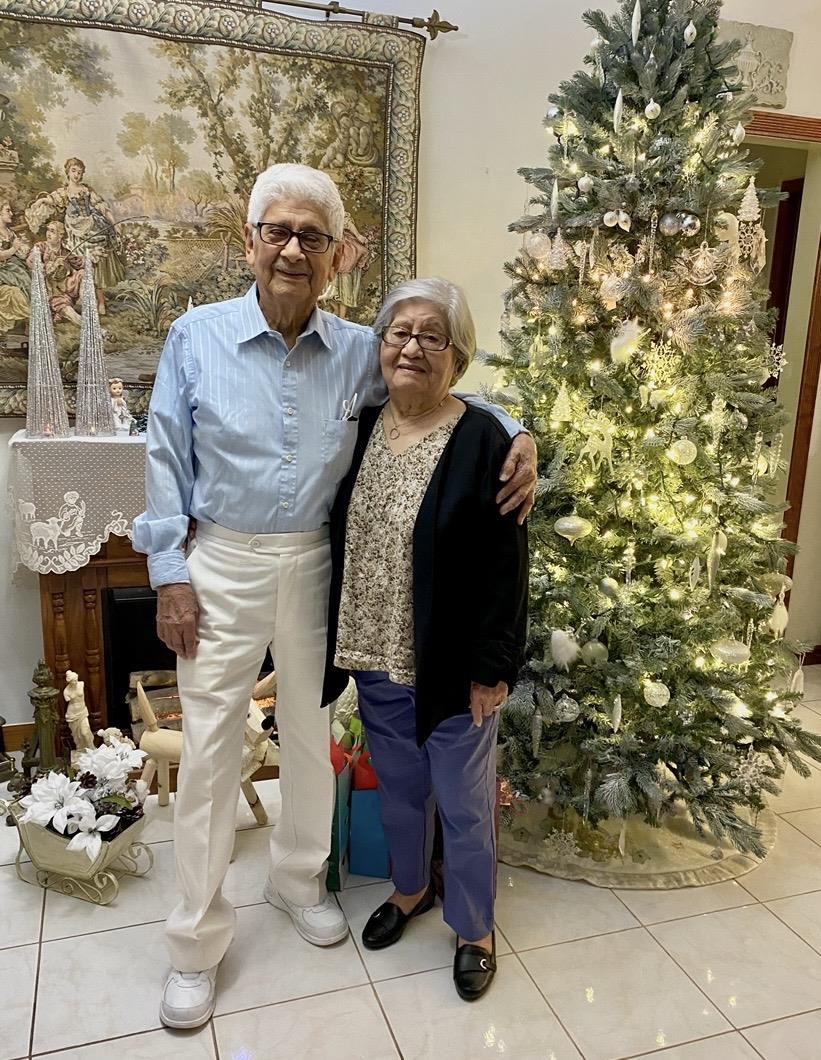 A man and woman standing in front of a christmas tree