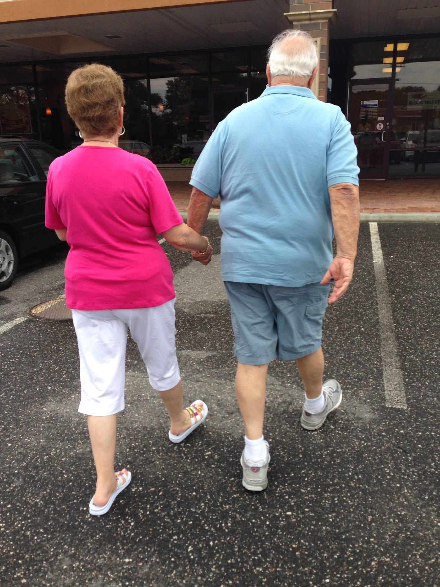 A man and woman holding hands walking in a parking lot