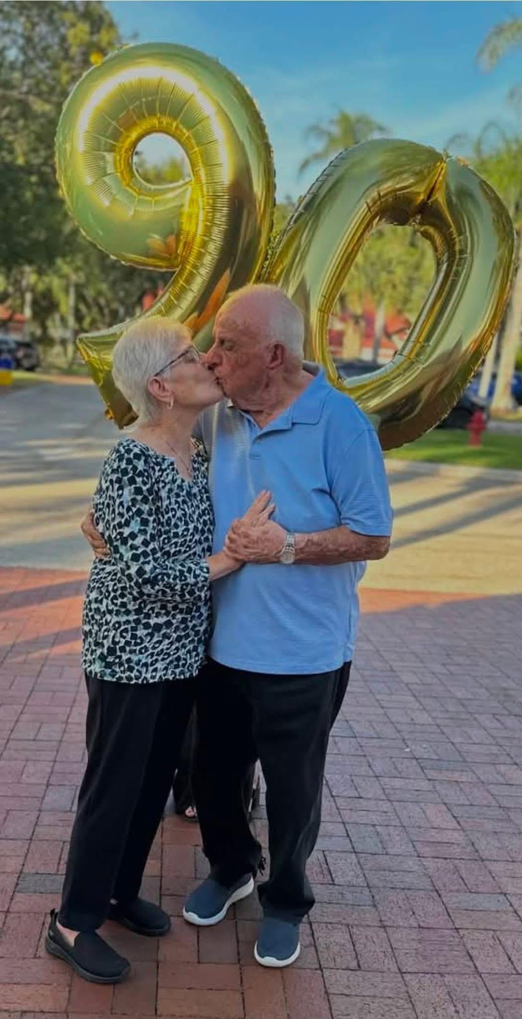 A man and woman kissing in front of a balloon