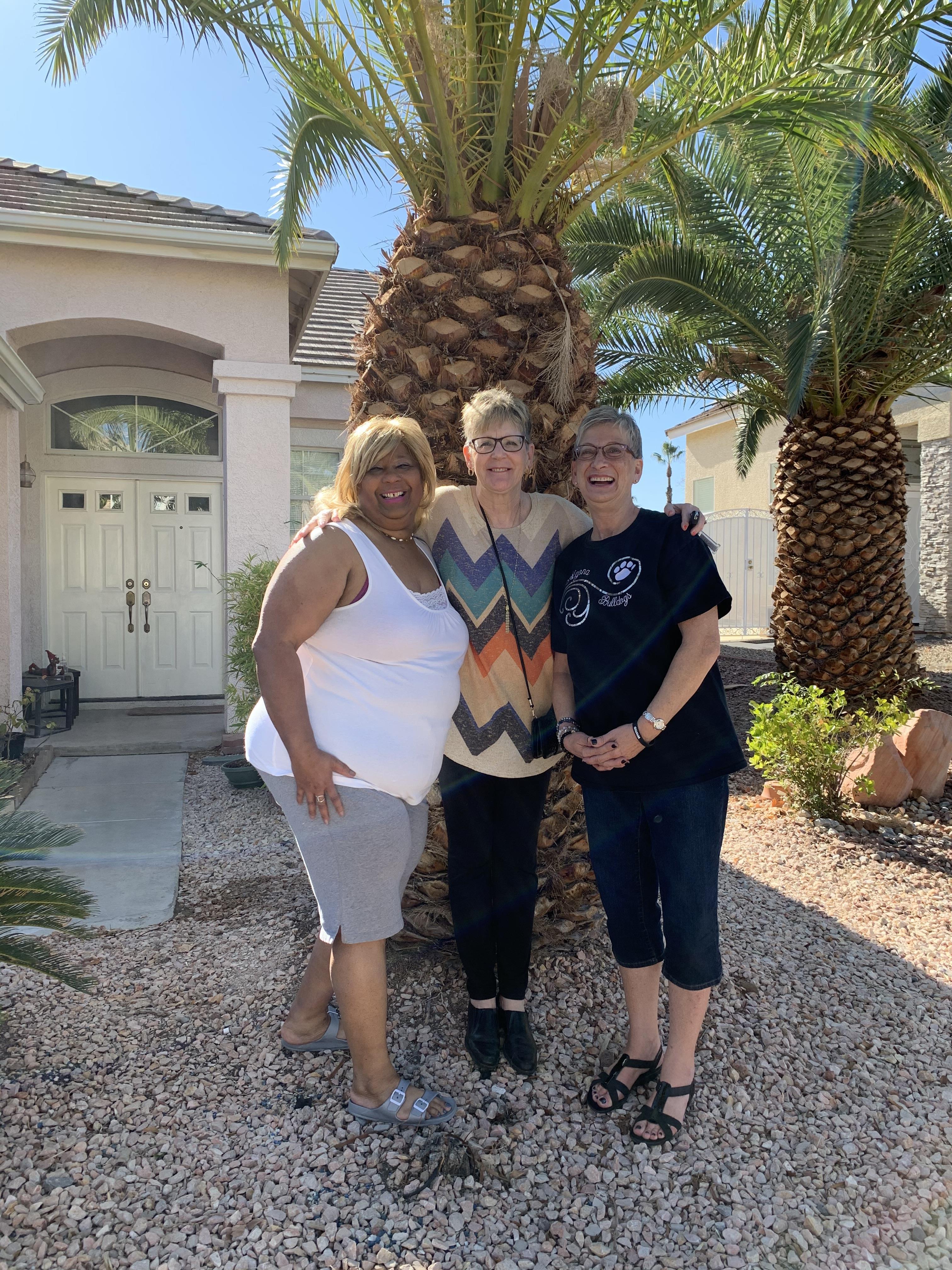 A group of women standing in front of a palm tree