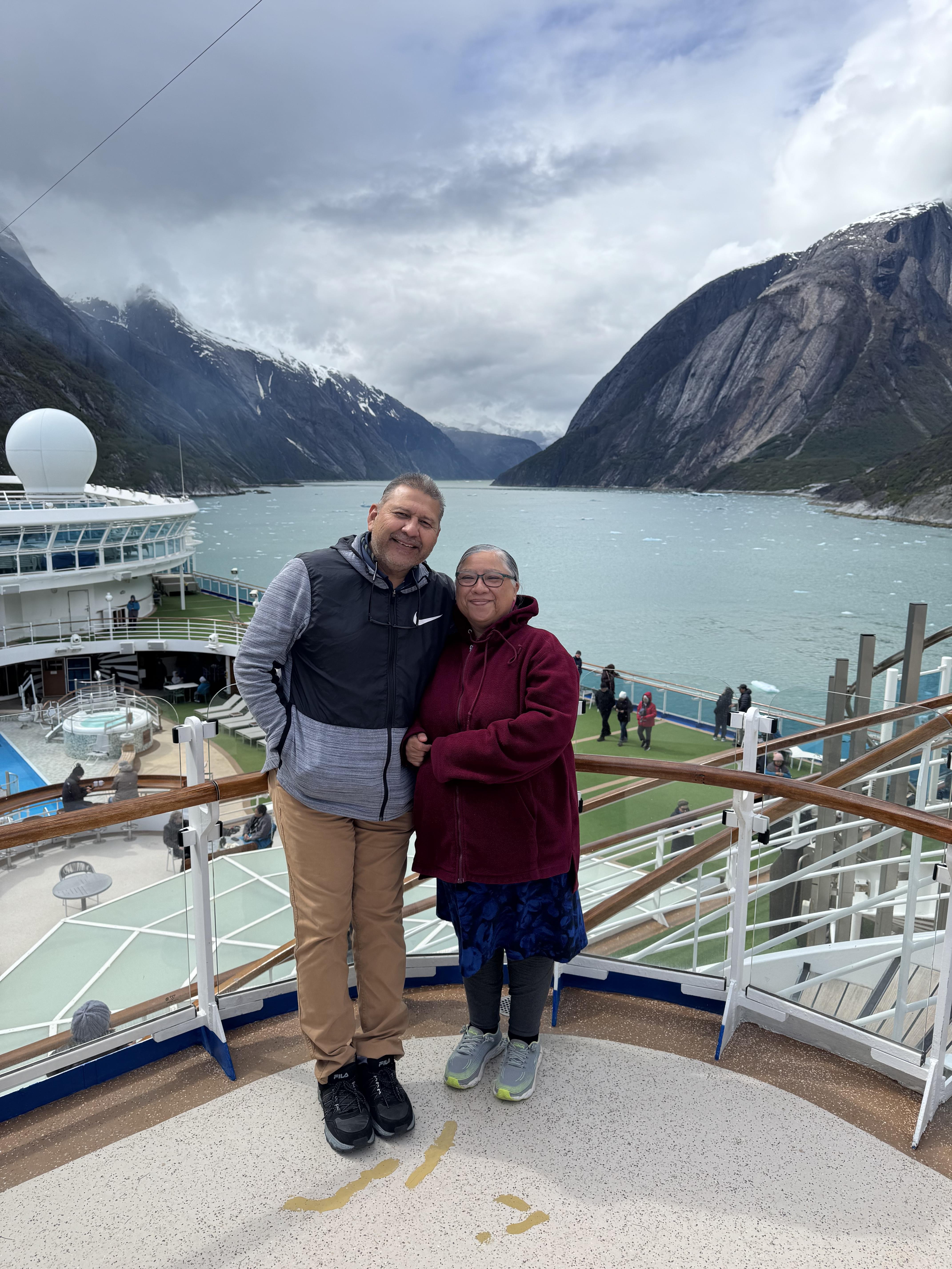 A man and woman posing for a picture on a deck of a cruise ship