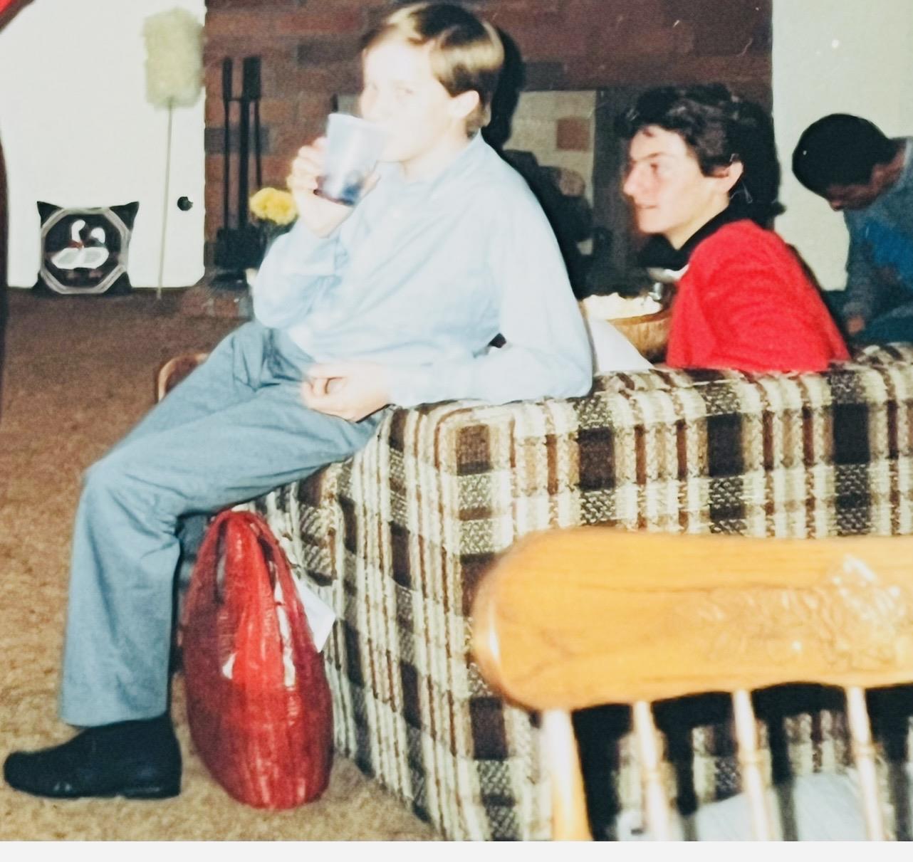 A boy sitting on a couch with a drink