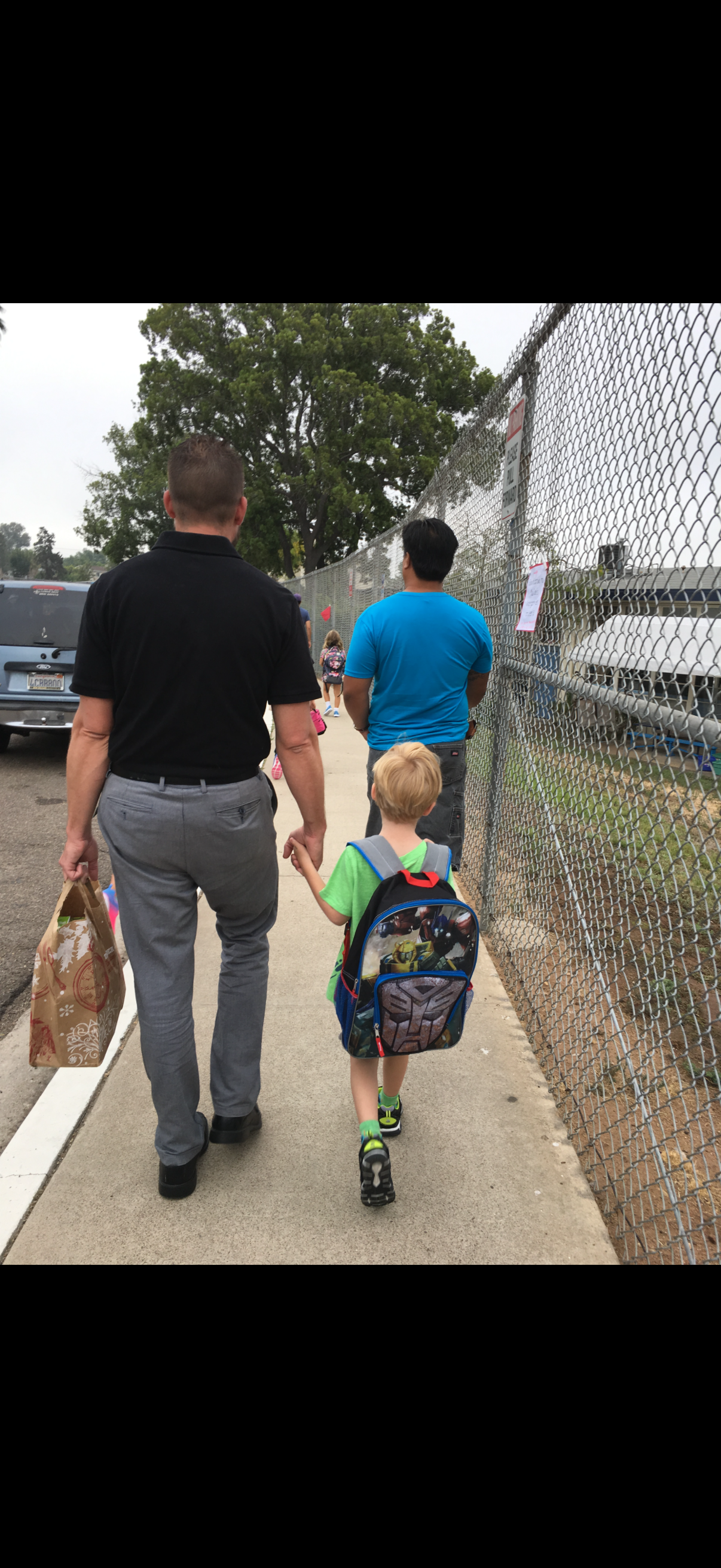 A man and child holding hands walking on sidewalk