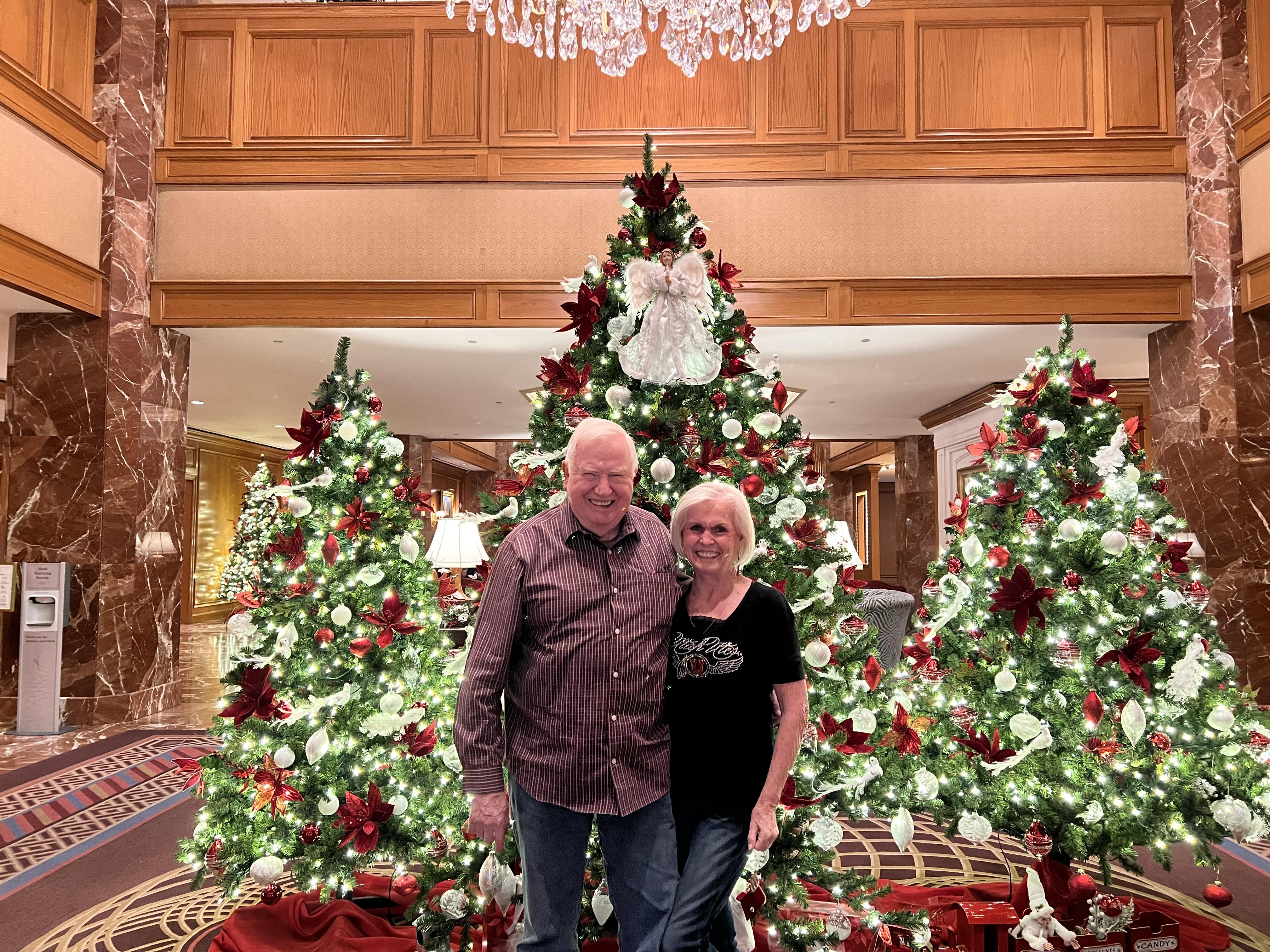 A man and woman standing in front of christmas trees